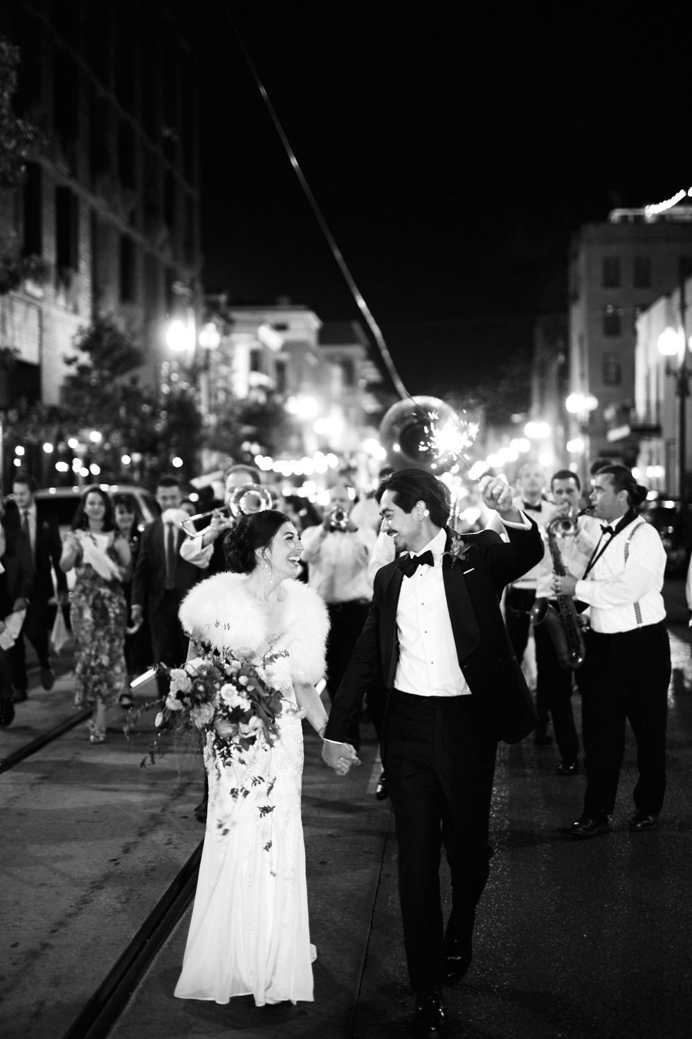 Festive nighttime wedding celebration on a city street with sparklers.