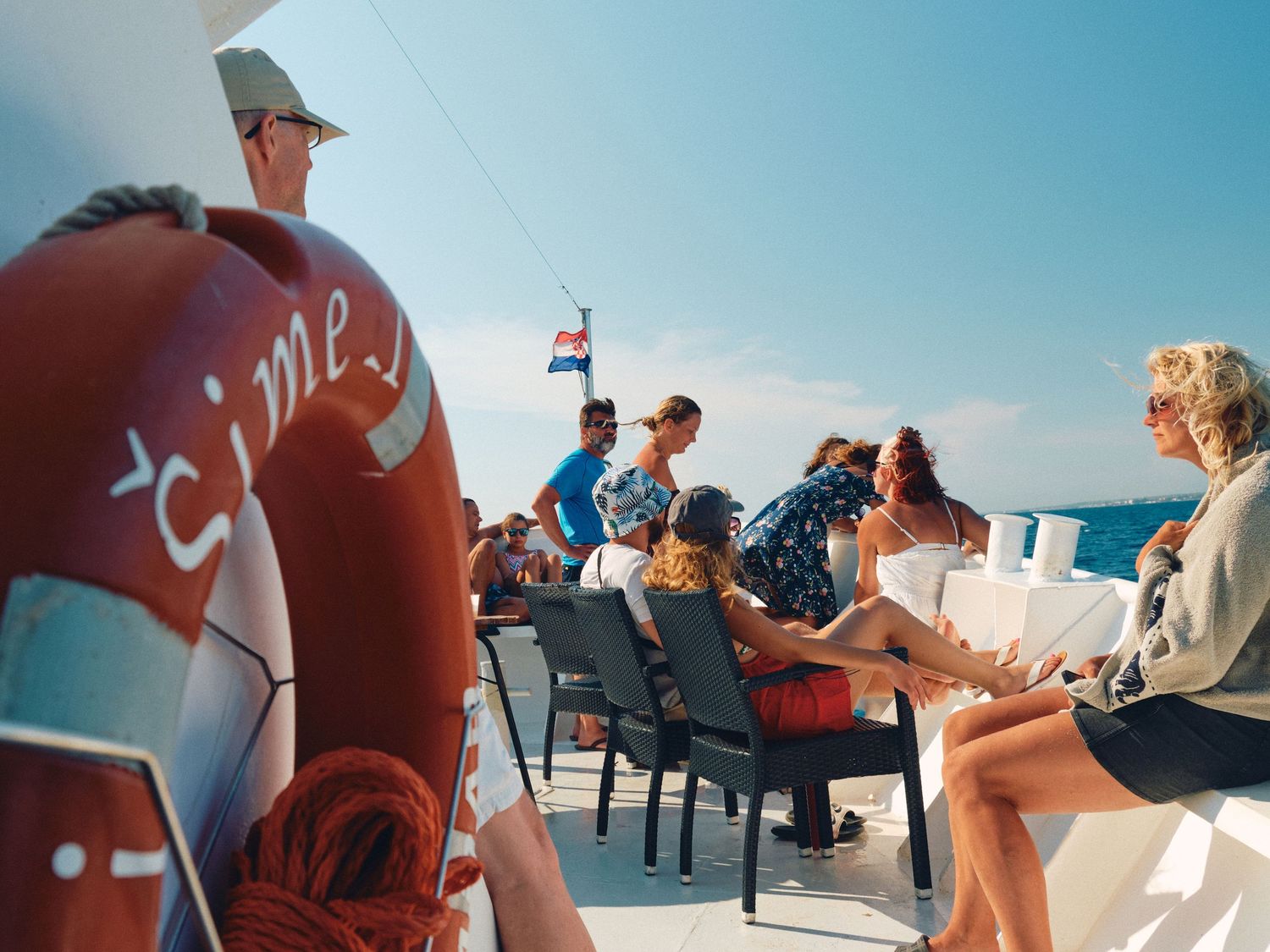 Passengers enjoying a scenic boat ride on the ocean with bright sunny skies and blue waters.