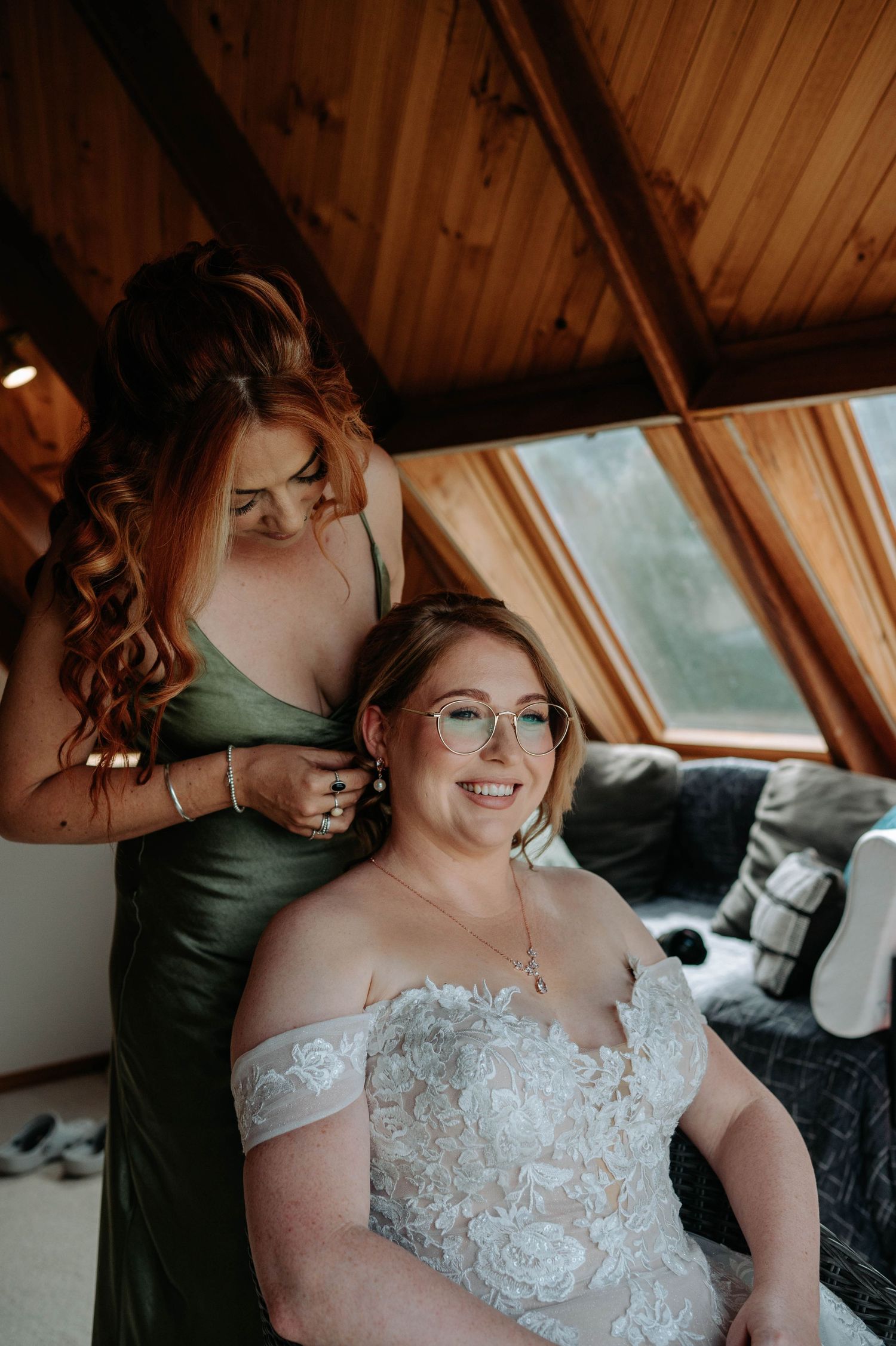 A touching bridal preparation moment in an attic space with wooden ceiling details.