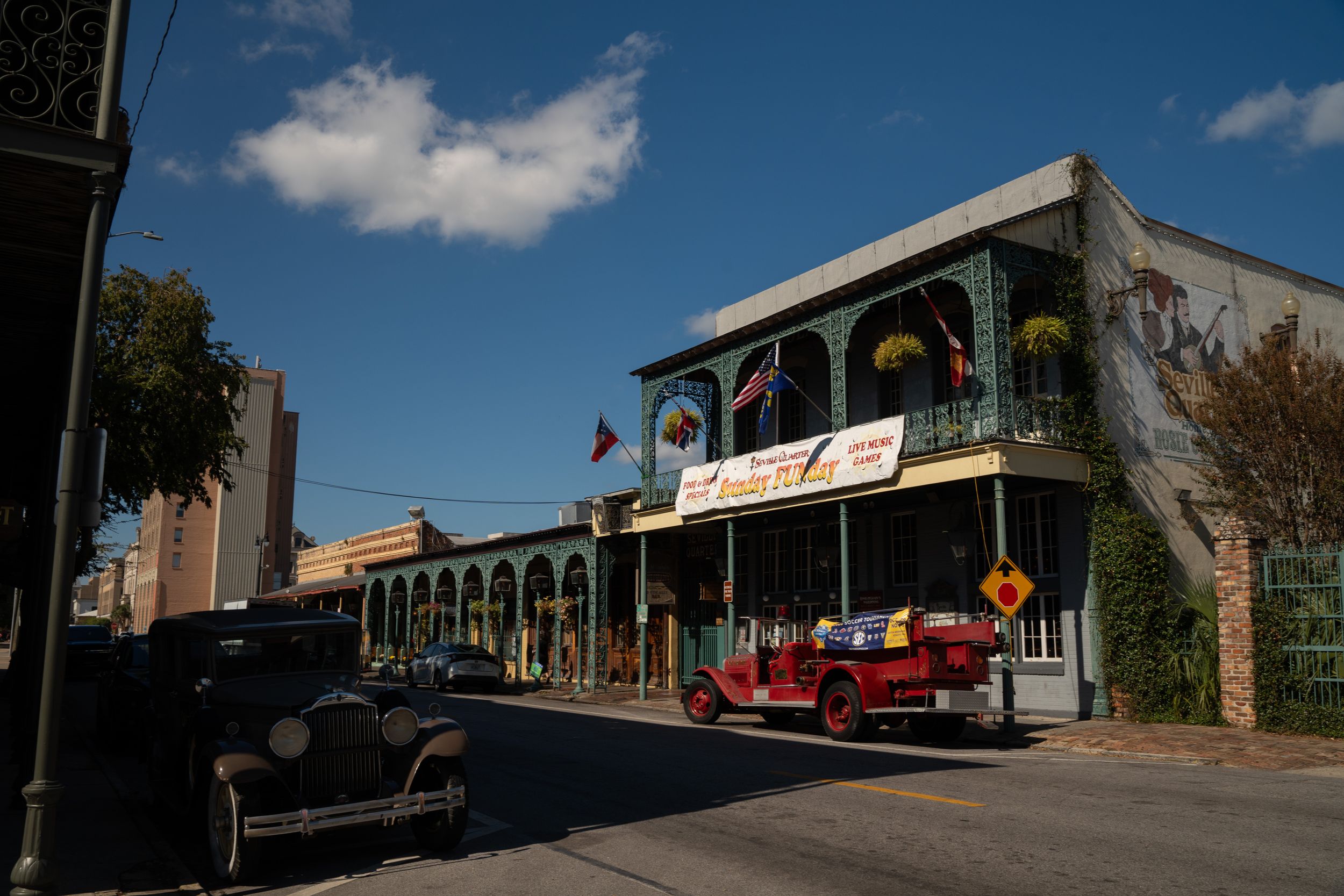 Historic brick building with ornate balcony and train car on display along a sunny street in small town America.