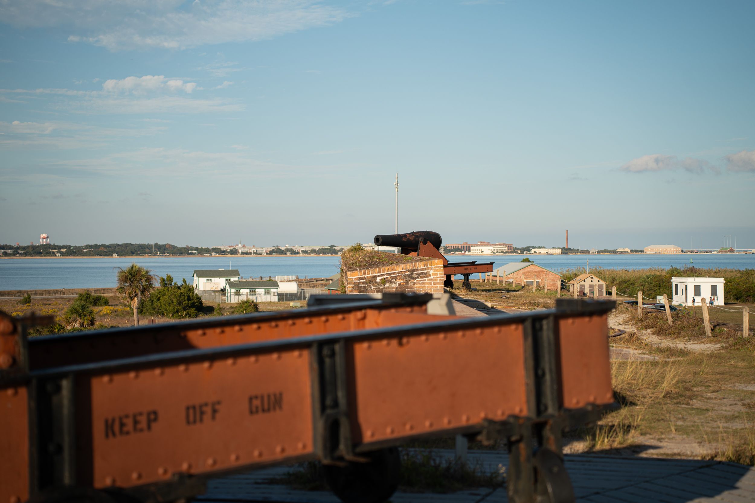 Orange train car overlooks a waterfront with boats and buildings visible along the coastal landscape.