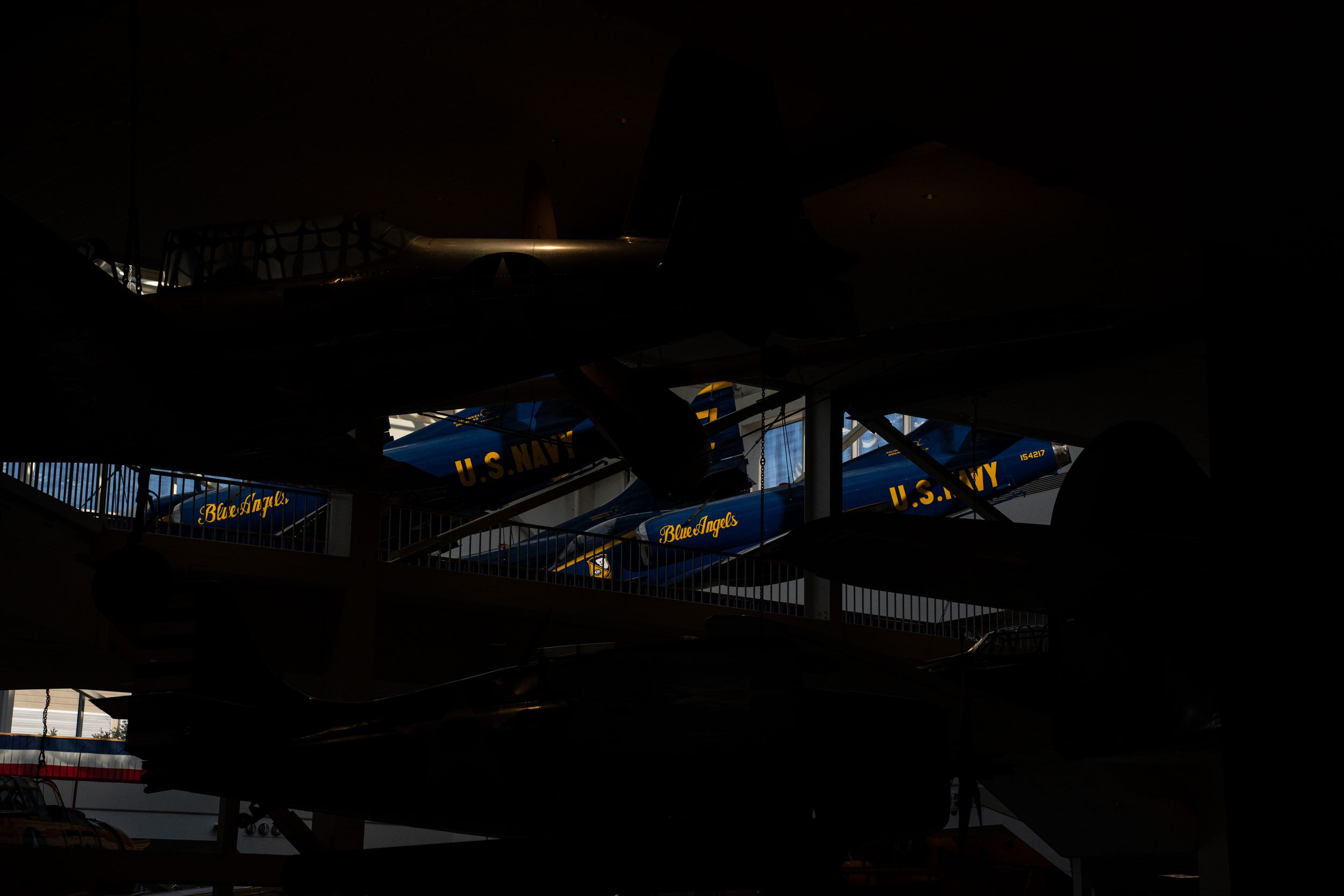 Dark interior rafters with scattered blue light shining through gaps creating an abstract pattern against black shadows.