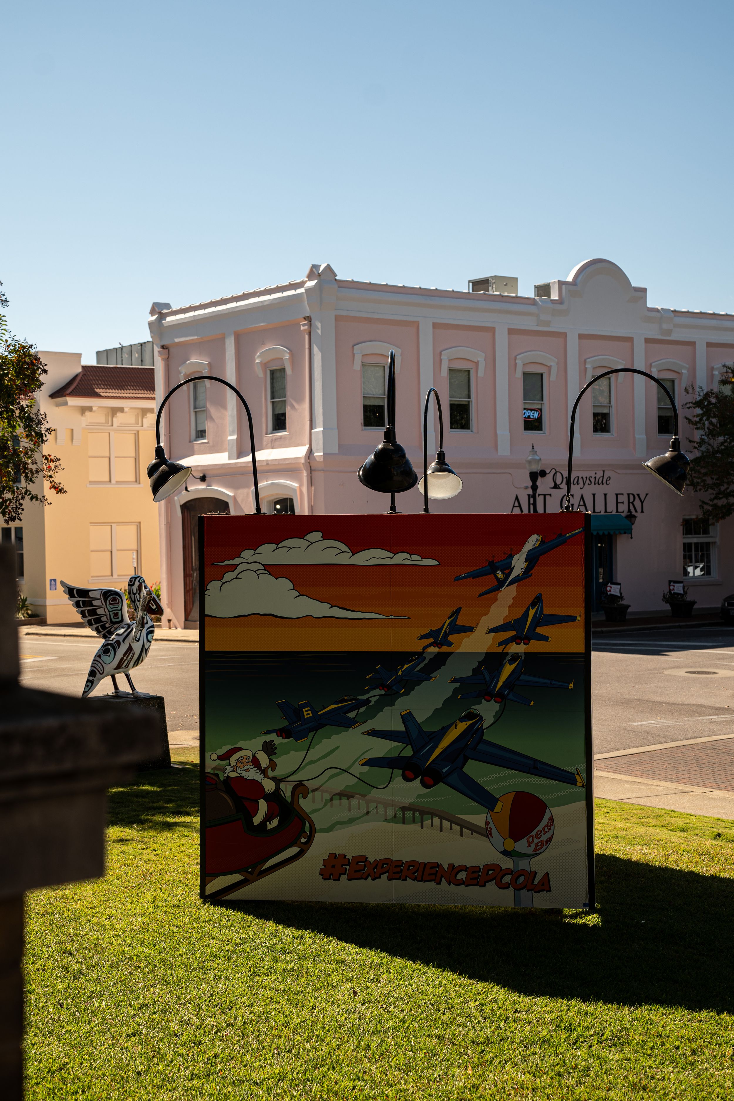 A vintage-style mural depicting wartime aircraft adorns a wall in front of a pink historic building.