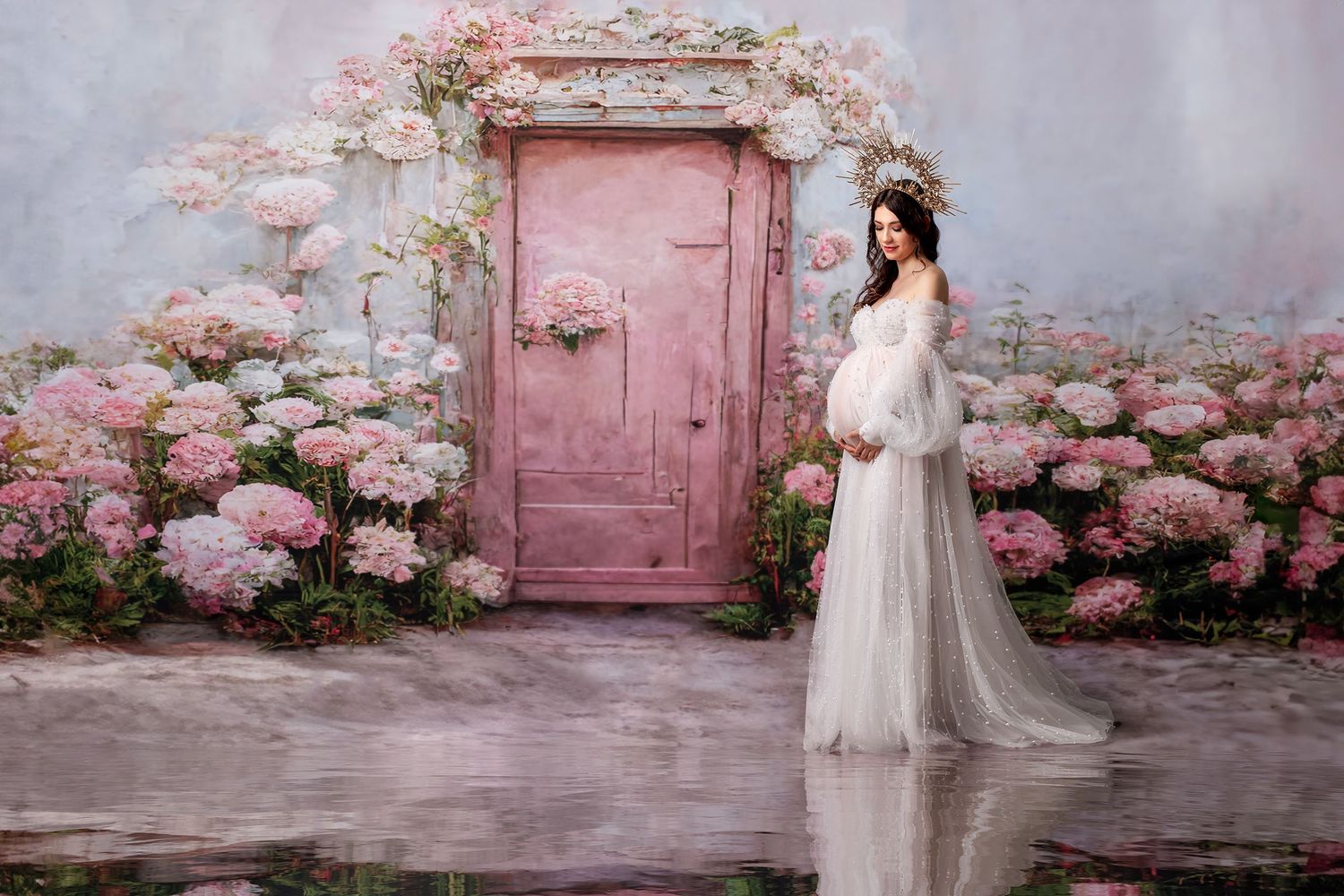 Expectant mother in a white pearl gown, looking peaceful in the studio setting.