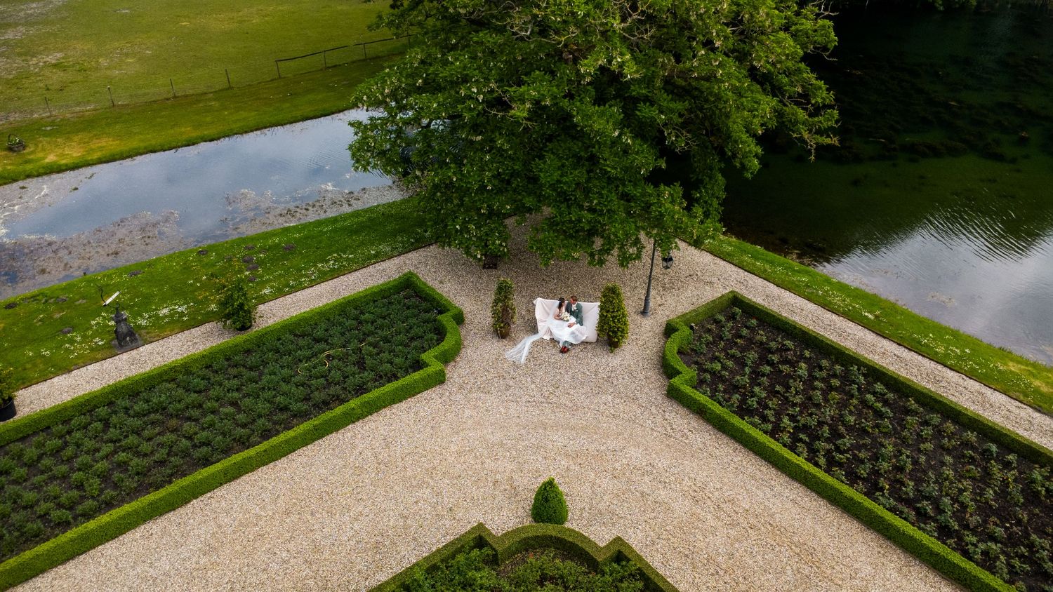 Bruidspaar zit op een bankje in een mooie kasteel tuin.
