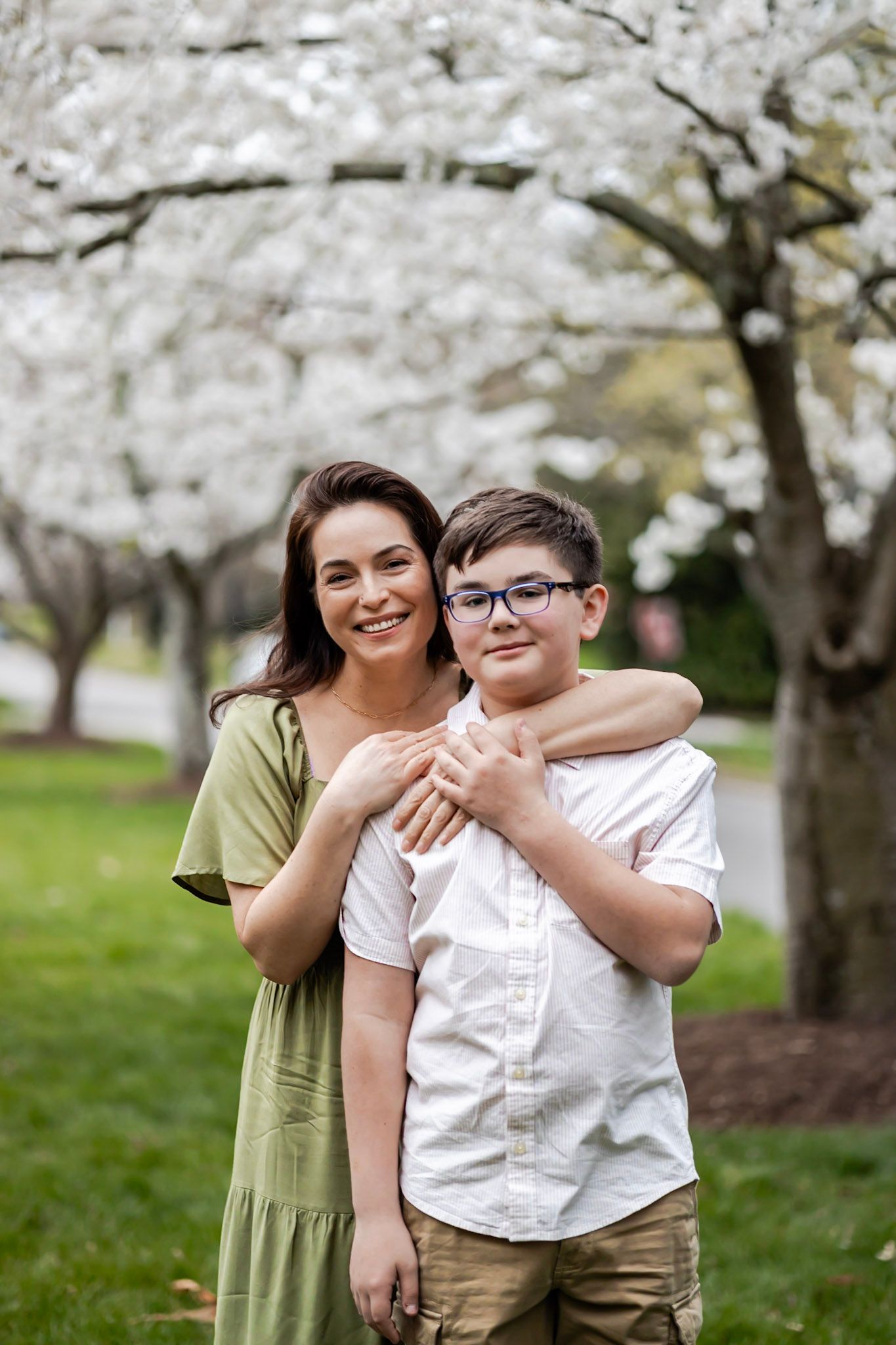 Two people share a tender embrace under blooming cherry blossom trees in a spring garden setting in Richmond, Virginia