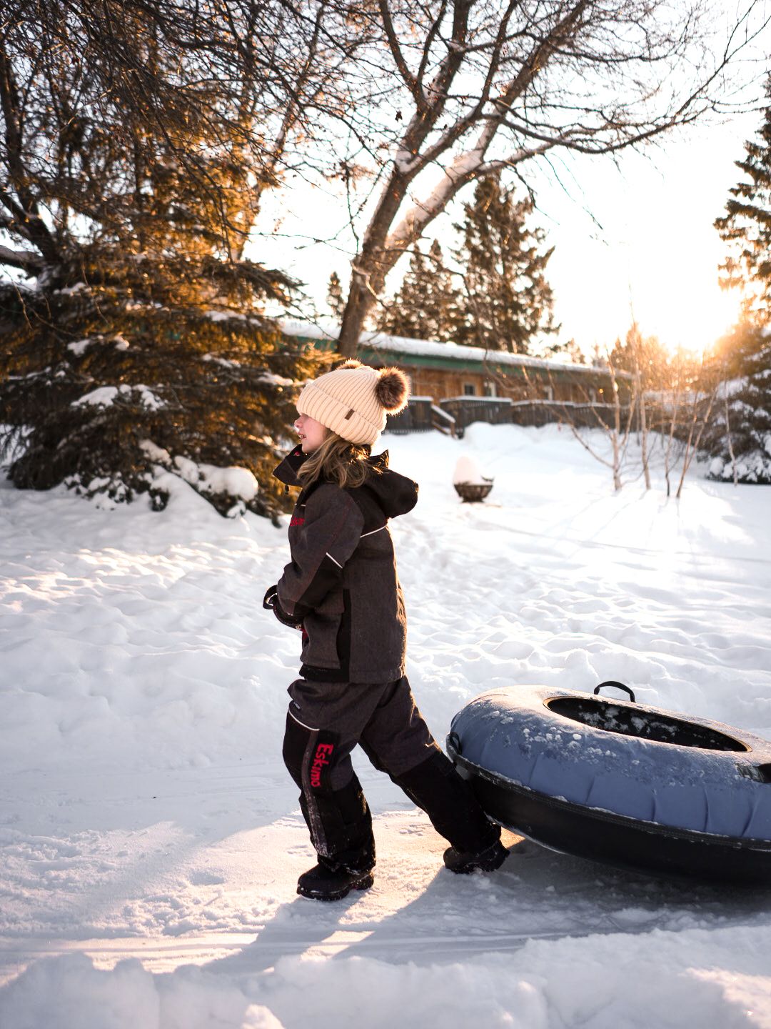 Winter snow tubing action sequence showing someone sliding down a snowy hill at sunset.