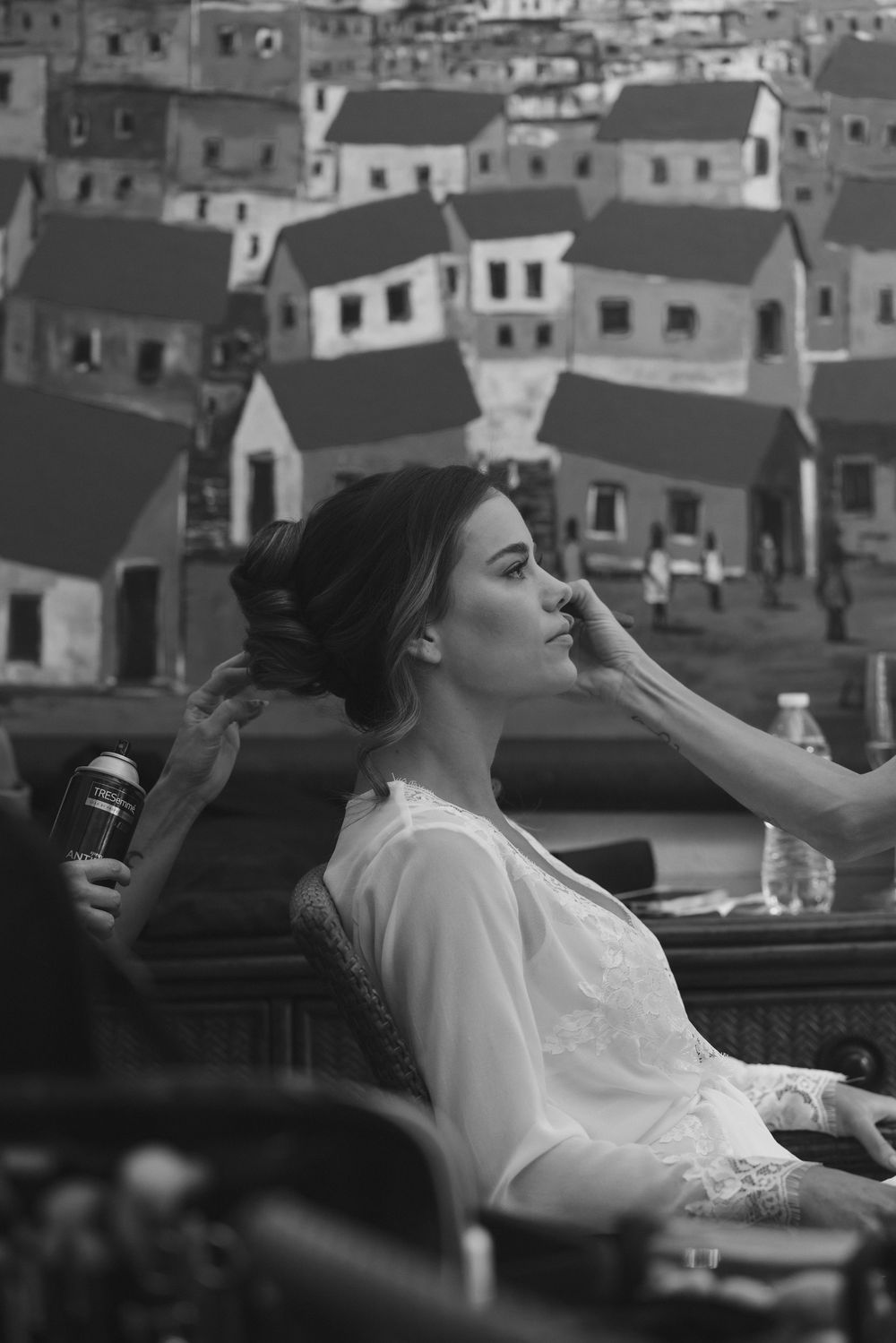 Black and white portrait showing wedding preparation against backdrop of hillside houses.