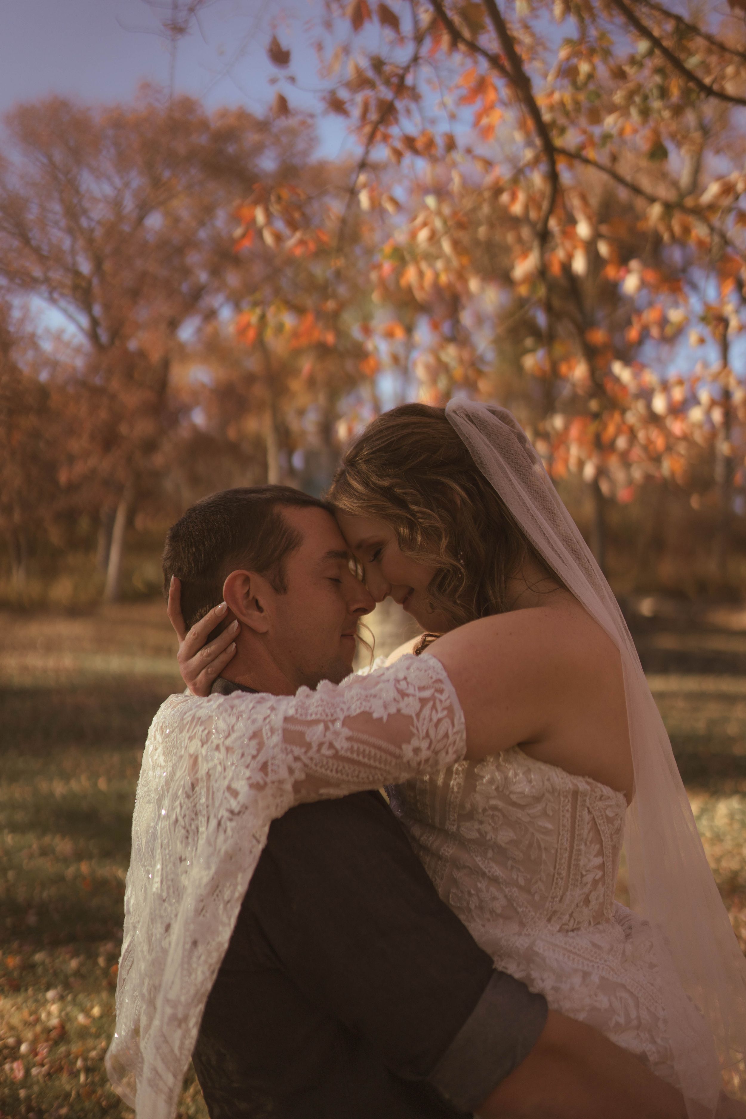 Intimate wedding portraits taken during golden hour with autumn leaves in background.