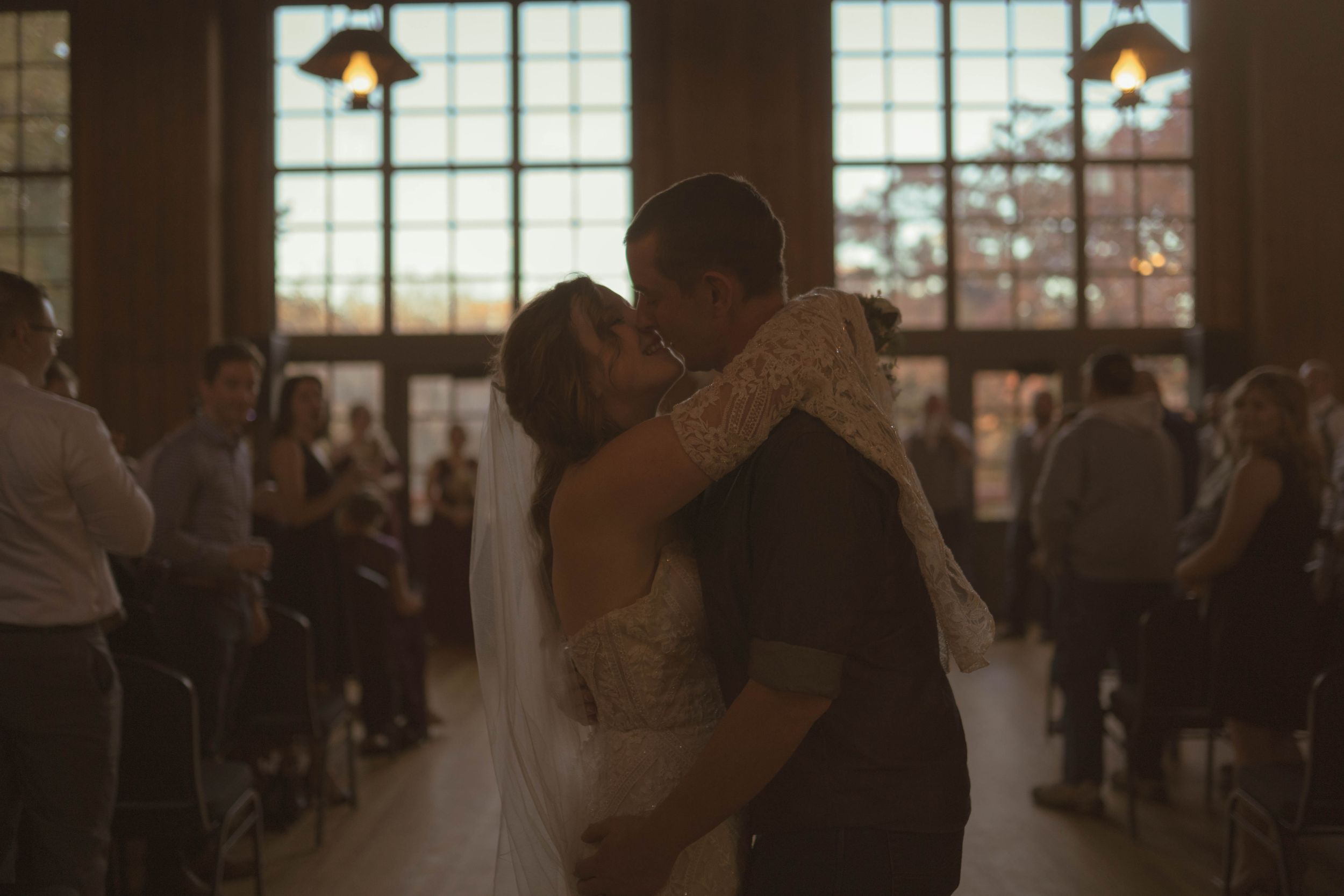 Couples dancing together during wedding reception in elegant venue with large windows.