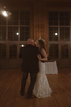 A romantic slow dance between newlyweds in a wooden-paneled reception hall.