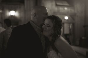 A tender moment between a couple dancing at a dimly lit wedding reception.