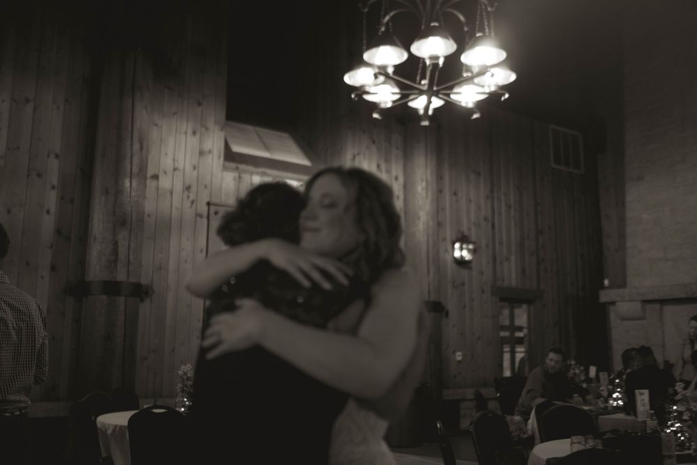 An emotional embrace captured during a wedding celebration in a rustic venue.