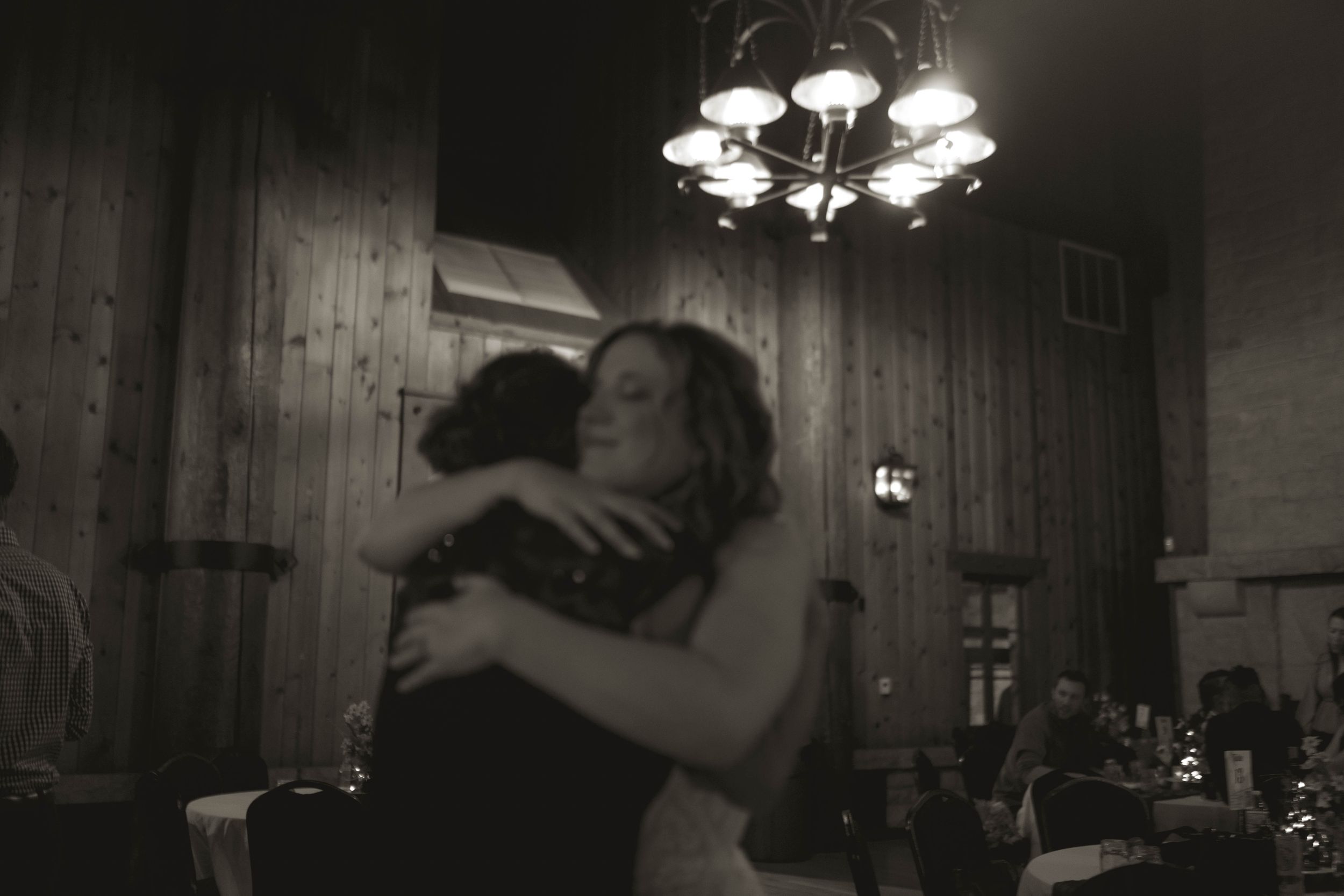 An emotional embrace captured during a wedding celebration in a rustic venue.
