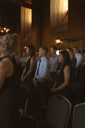 Wedding reception guests seated in dimly lit rustic wooden venue.