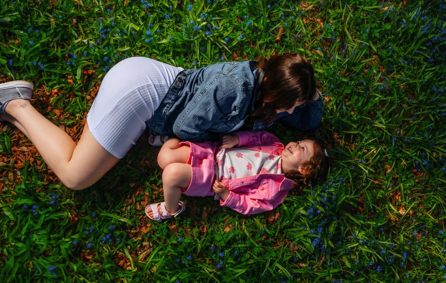 A playful moment captured lying on lush green grass on a sunny day.
