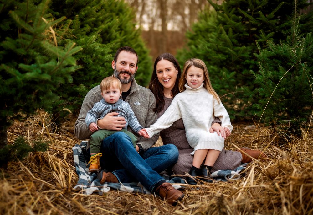 Natural outdoor family photography session among evergreen trees and straw.