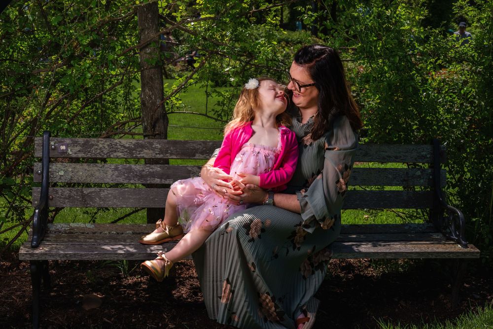 A heartwarming scene unfolds on a park bench surrounded by lush green trees.