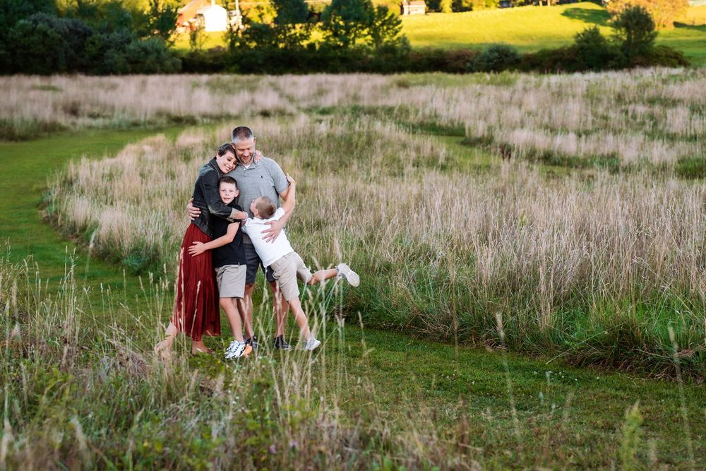 A golden sunset illuminates a grassy field with tall natural grasses.