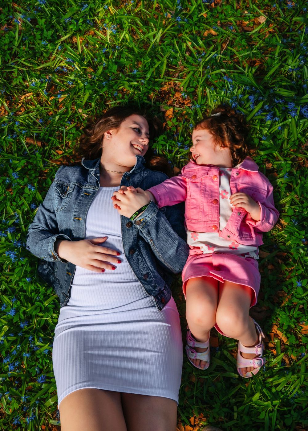 A heartwarming moment of laughter while lying on grass together outdoors.