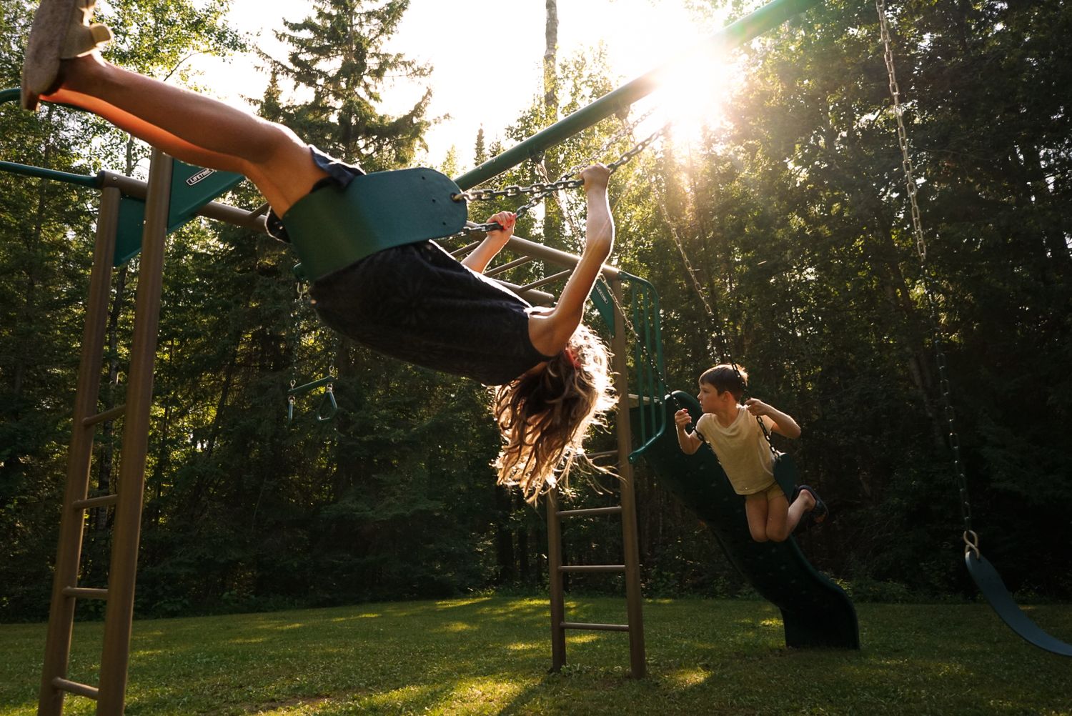 People swinging on swings at a beach camp during golden hour sunset.