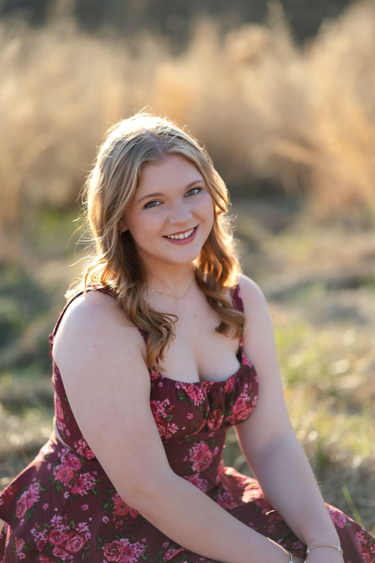 A person in a flowing white dress stands among tall golden grass at sunset, with sunlight creating a dreamy glow.
