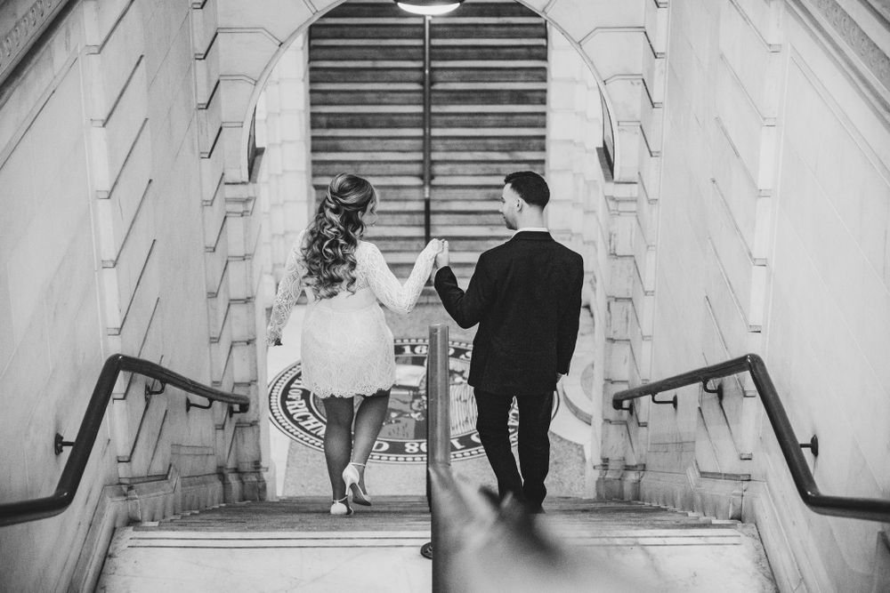 Elegant couple dancing on marble steps in a grand architectural setting.