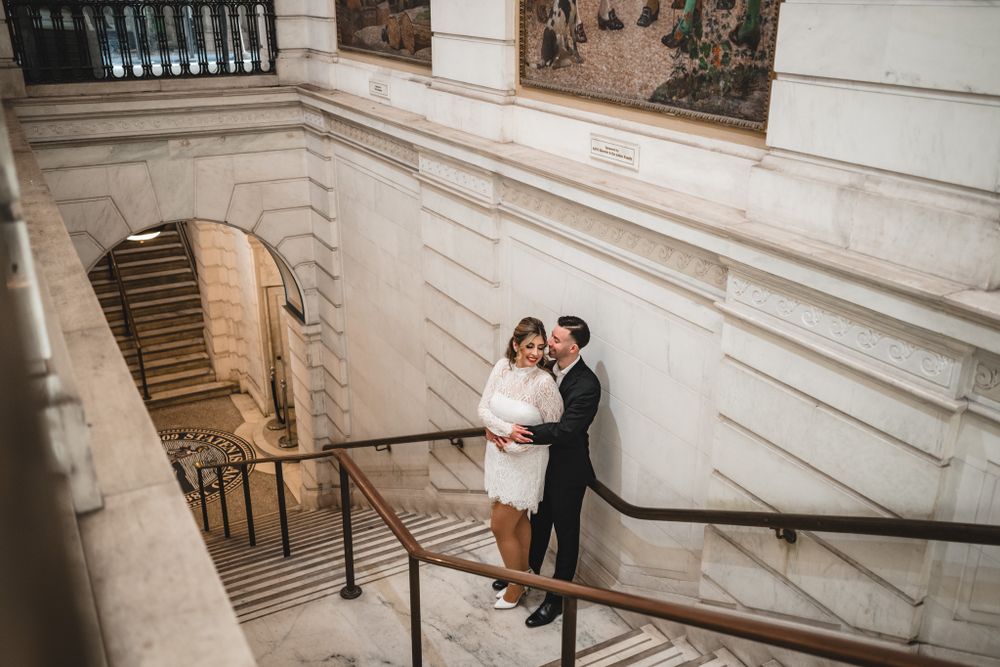 Wide angle view of couple on elegant marble staircase with classical architecture.