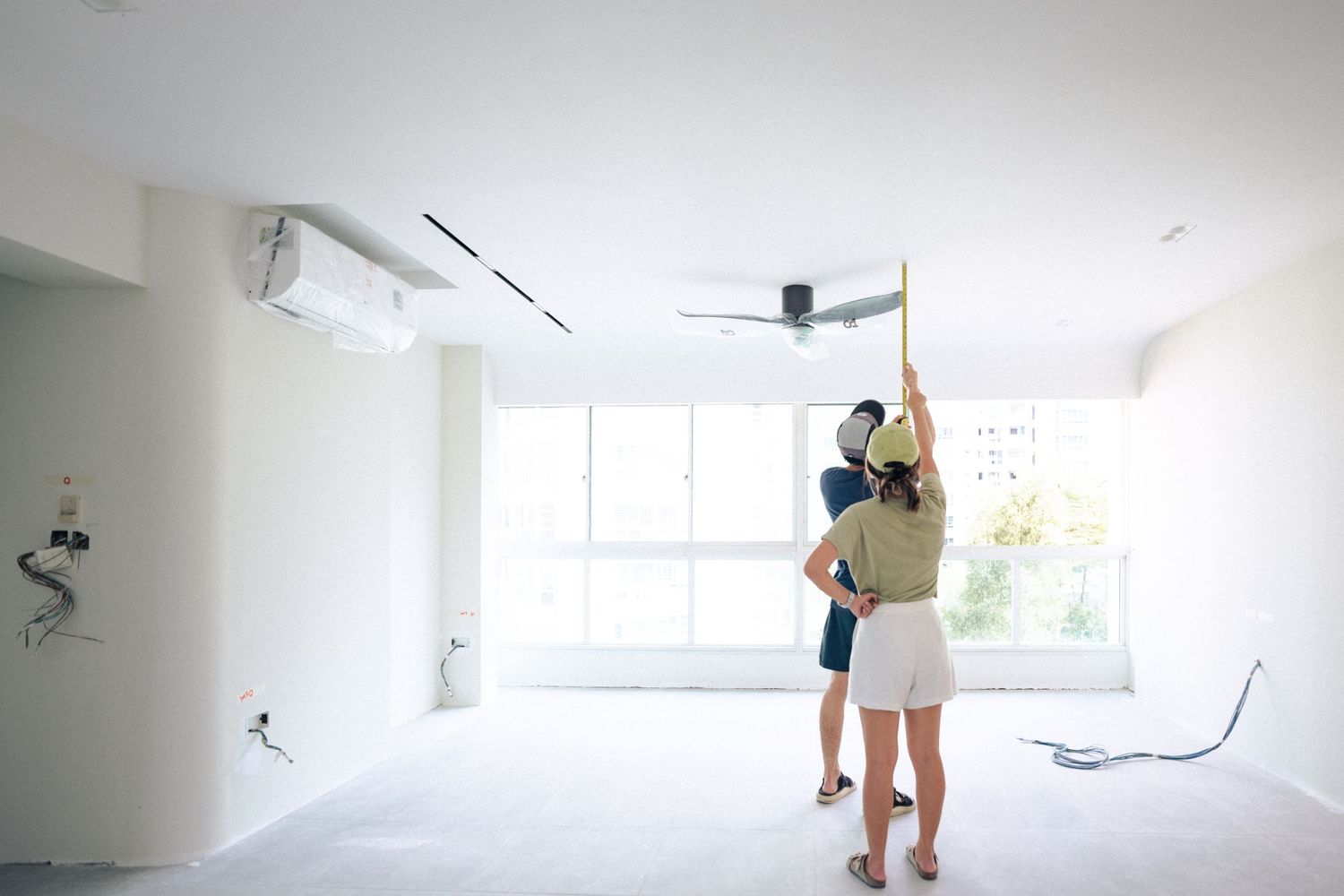 Two people dance together in an empty white room with large windows and exposed ductwork on the ceiling.