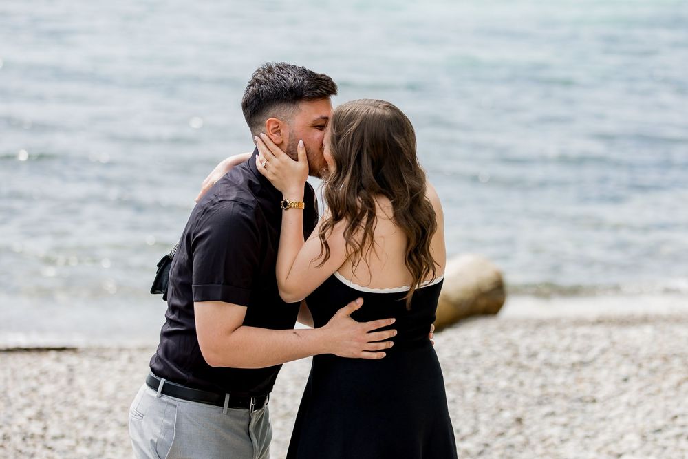 Couple sharing intimate moment on rocky beach during proposal.