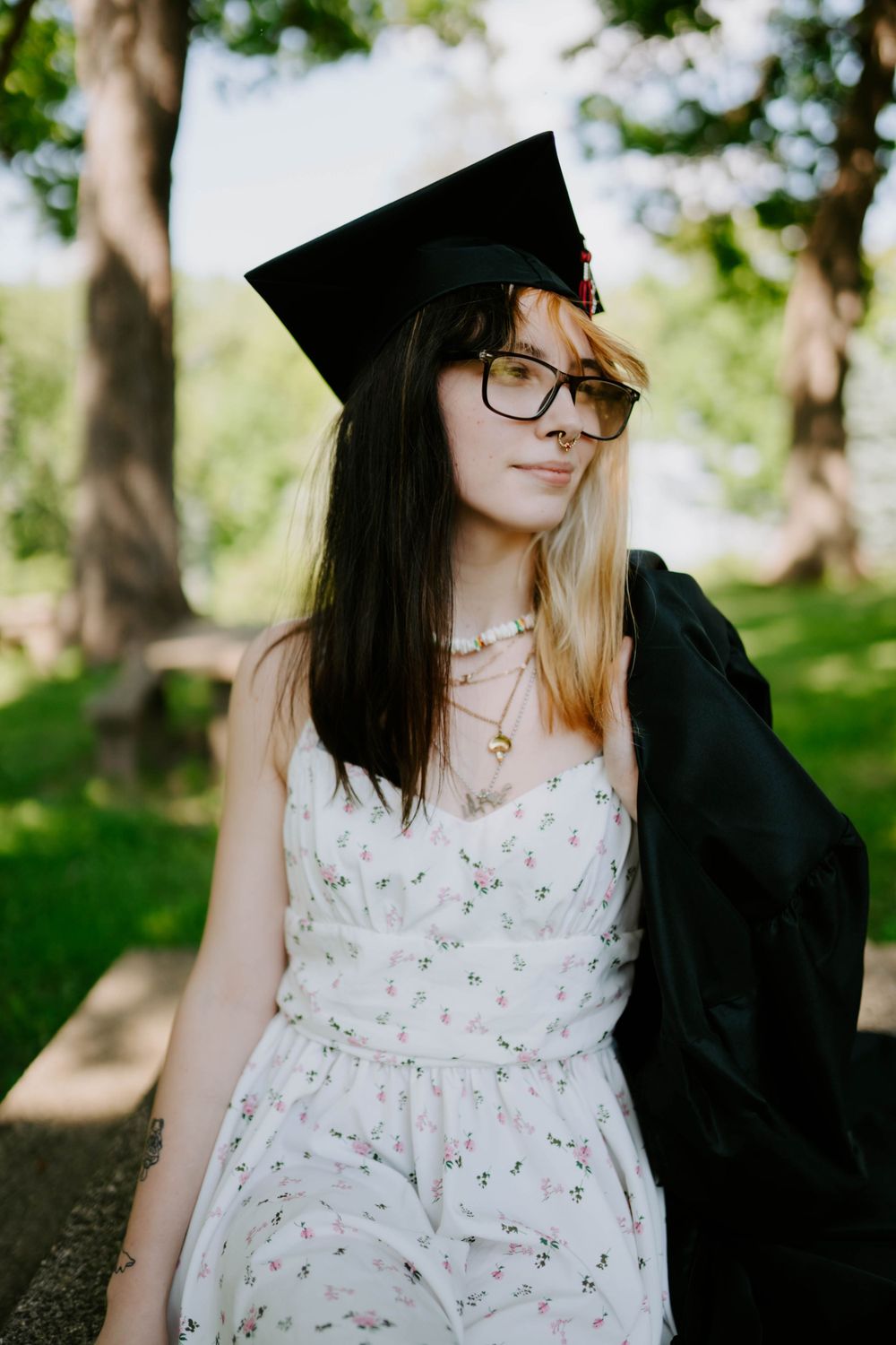 Graduation portraits featuring black cap and gown with floral dress underneath.