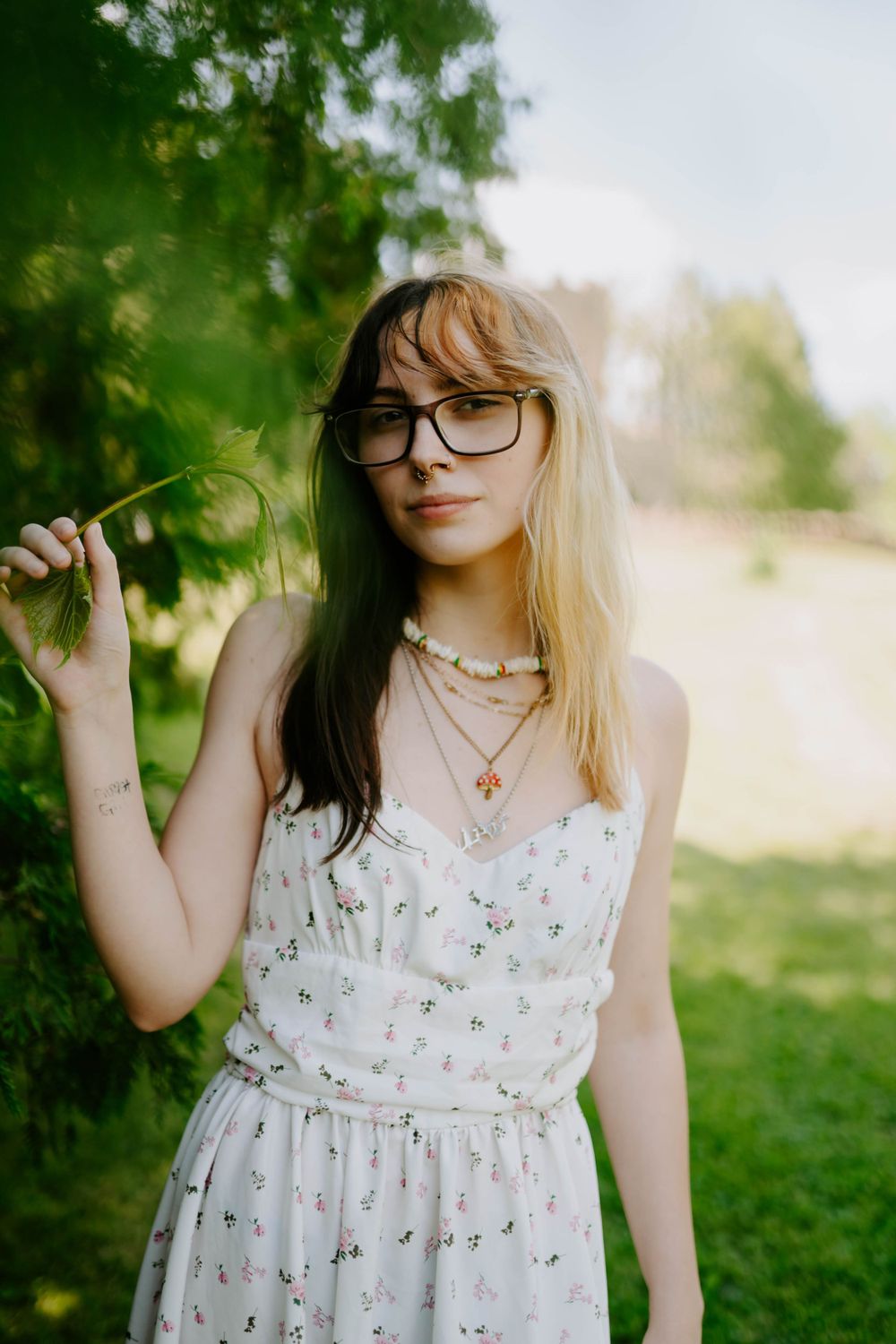 Summer portrait of someone wearing a white floral sundress in a garden setting.