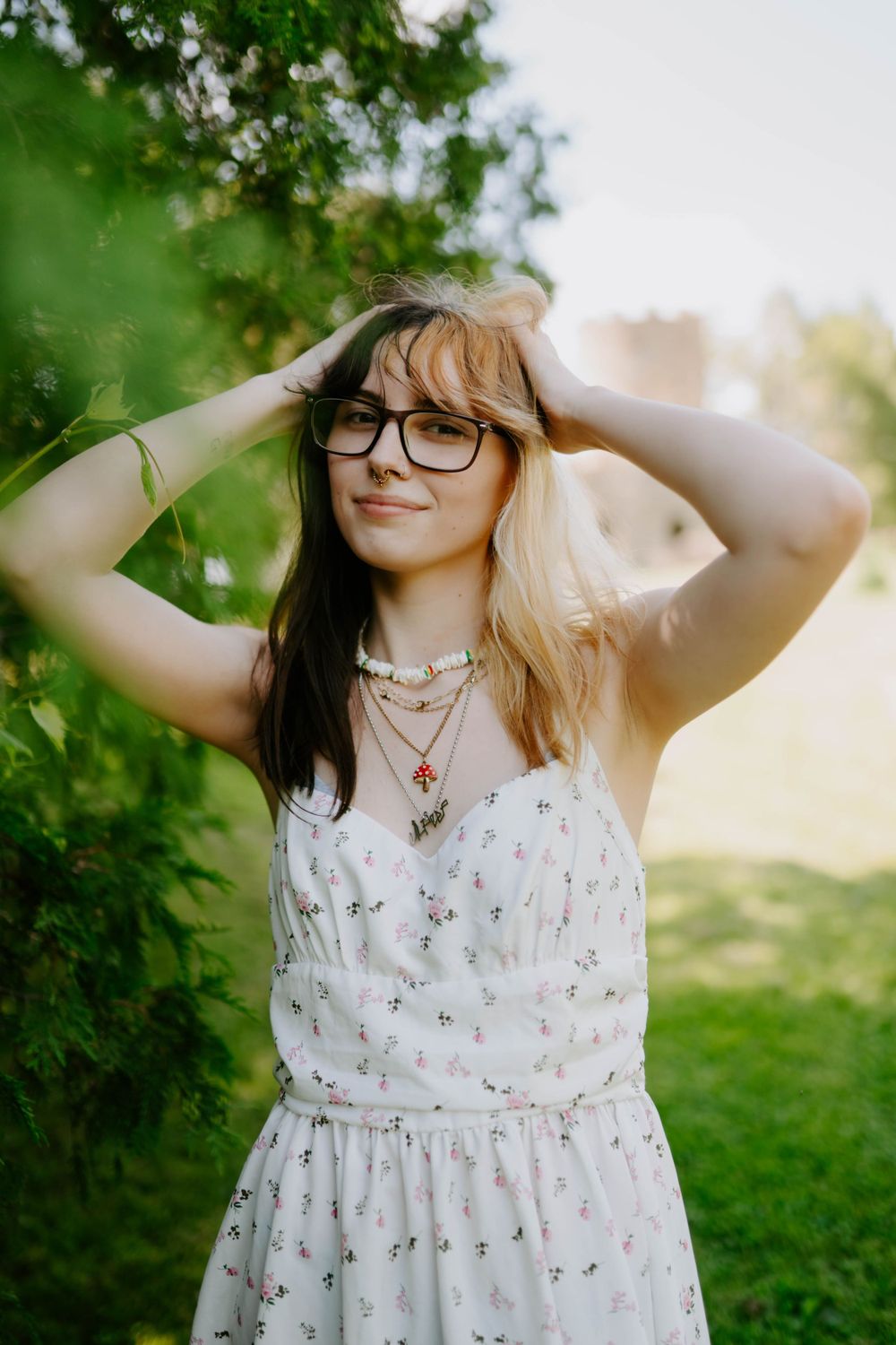 Candid outdoor photoshoot featuring white floral dress against green foliage background.