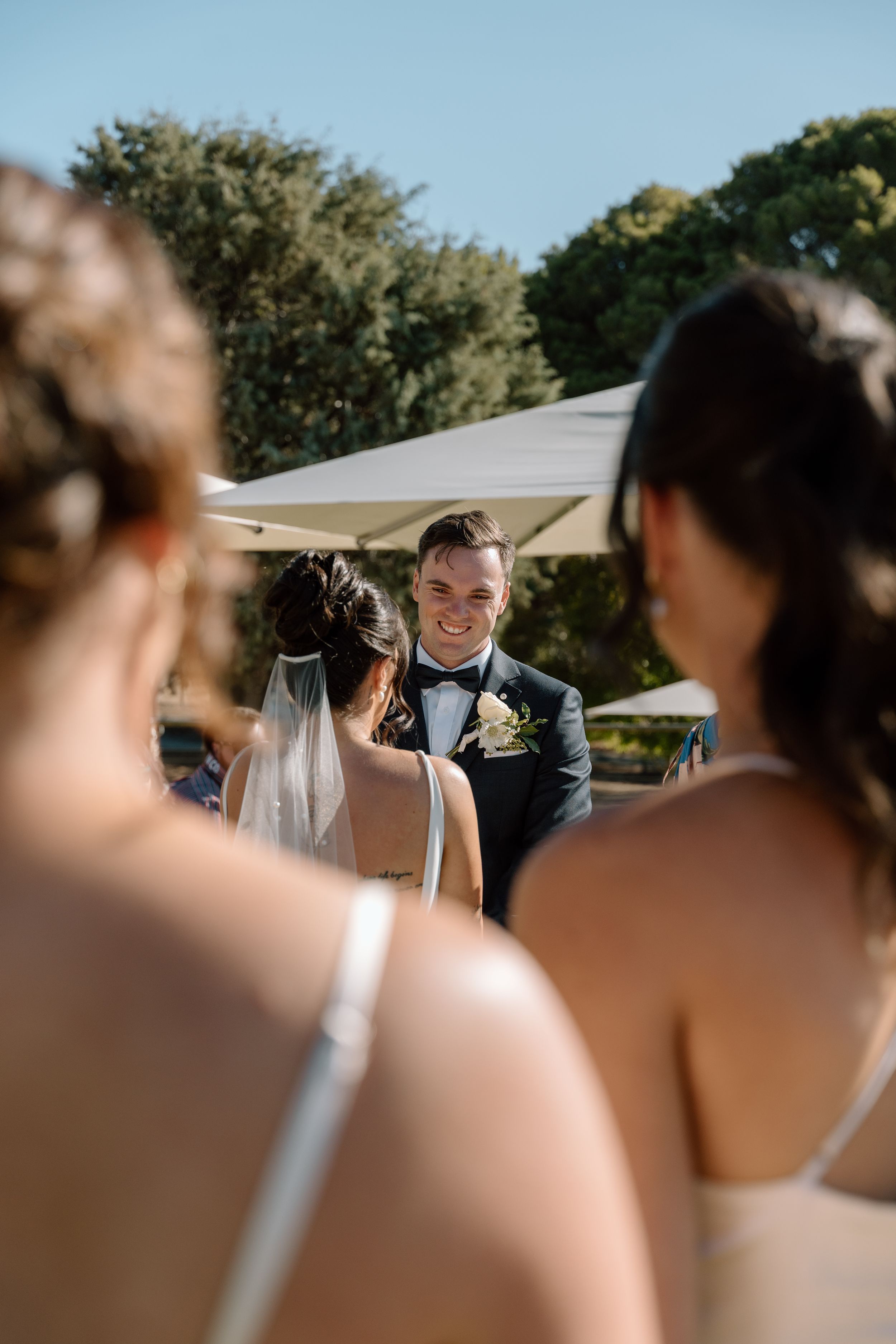 Wedding party shares joyful laughter during an outdoor celebration on a sunny day.