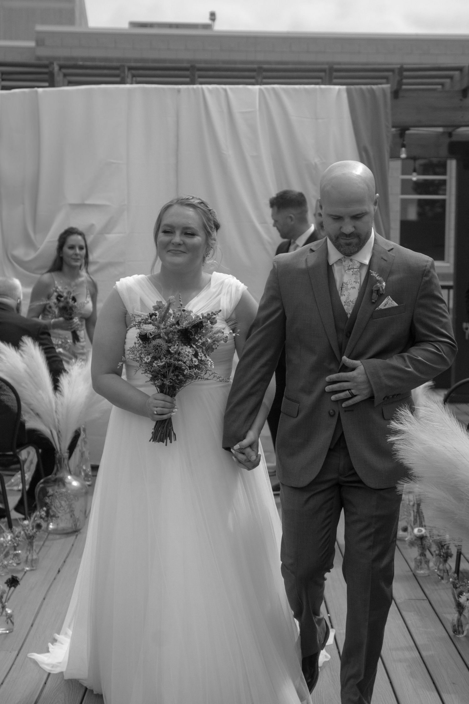 A couple walks down the aisle together after their wedding ceremony in black and white photography.