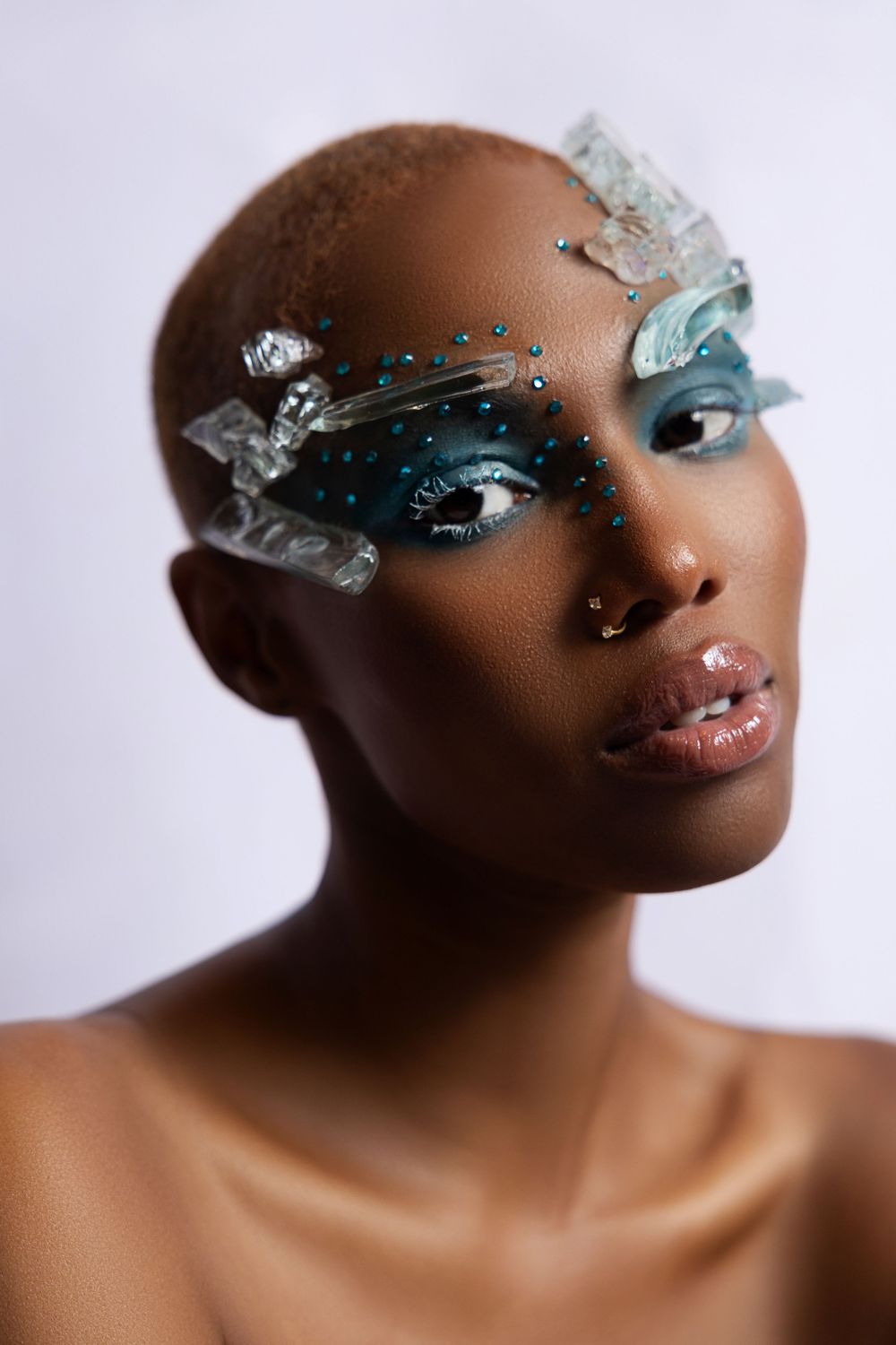 Creative beauty portrait with ice-like crystal eye makeup and bare shoulders.