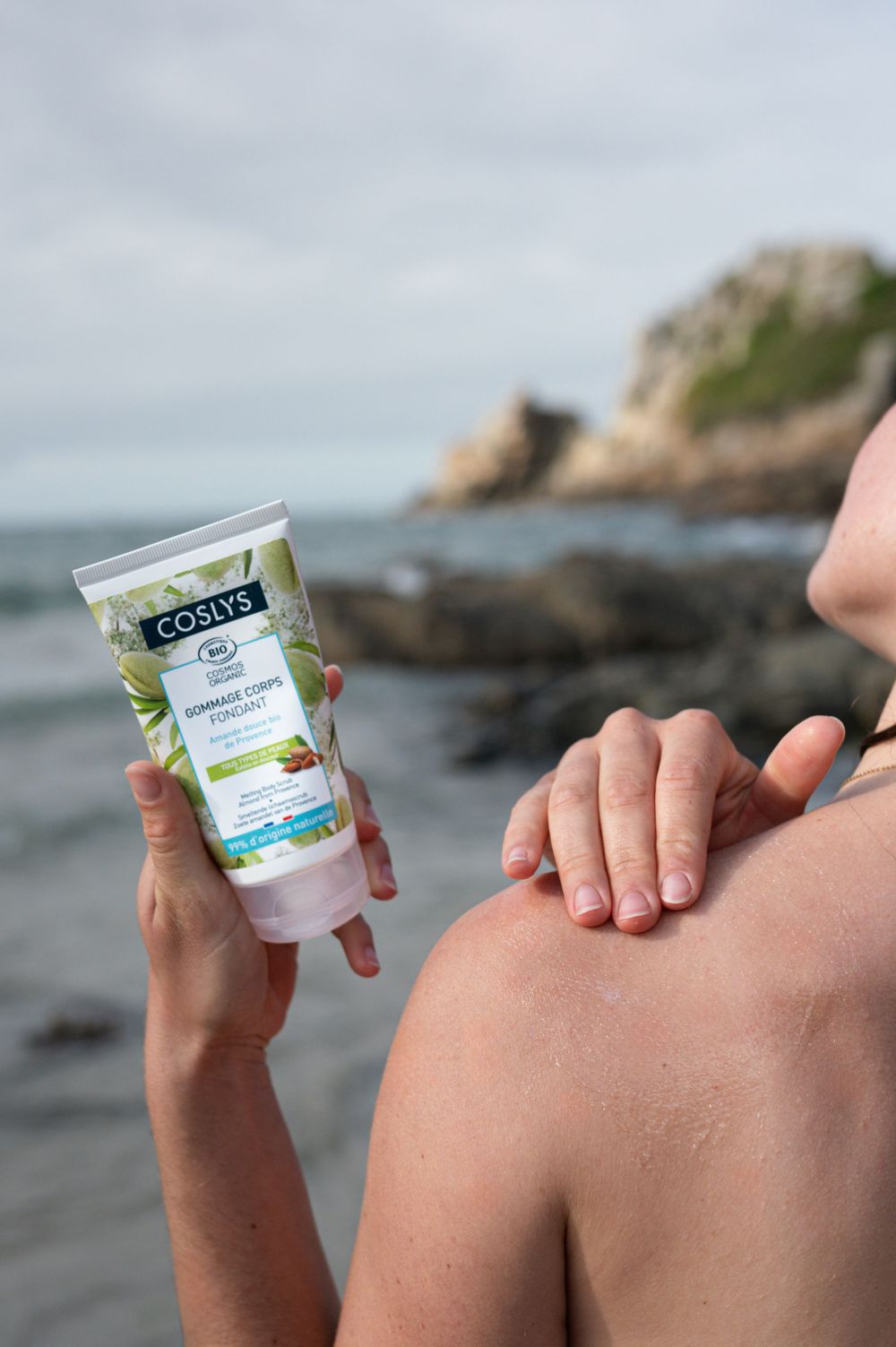 Appliquer à la main un produit solaire naturel sur la côte rocheuse de la plage.