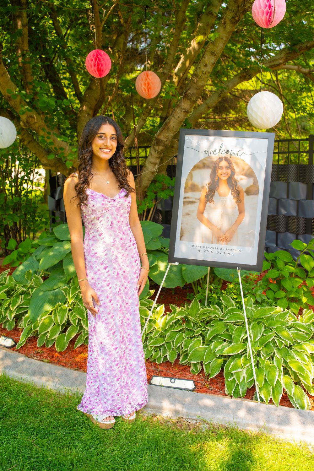A pink floral summer dress and garden party decorations including balloons create a festive outdoor celebration scene Quad Cities Graduation