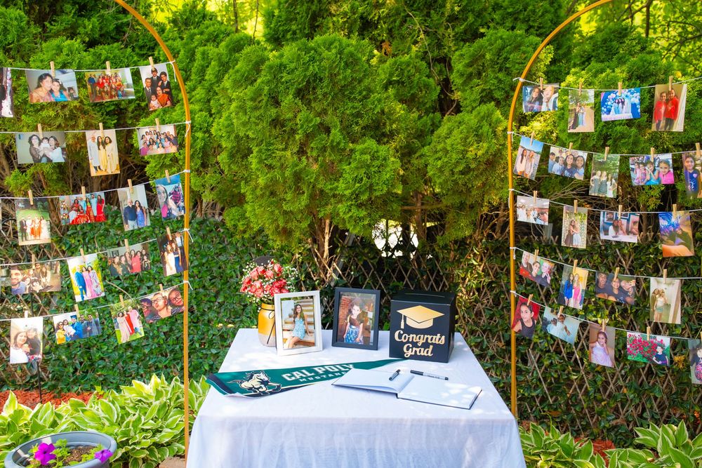 A string of photographs hanging on a clothesline outdoors against lush green foliage. Quad Cities Graduation Event Photography