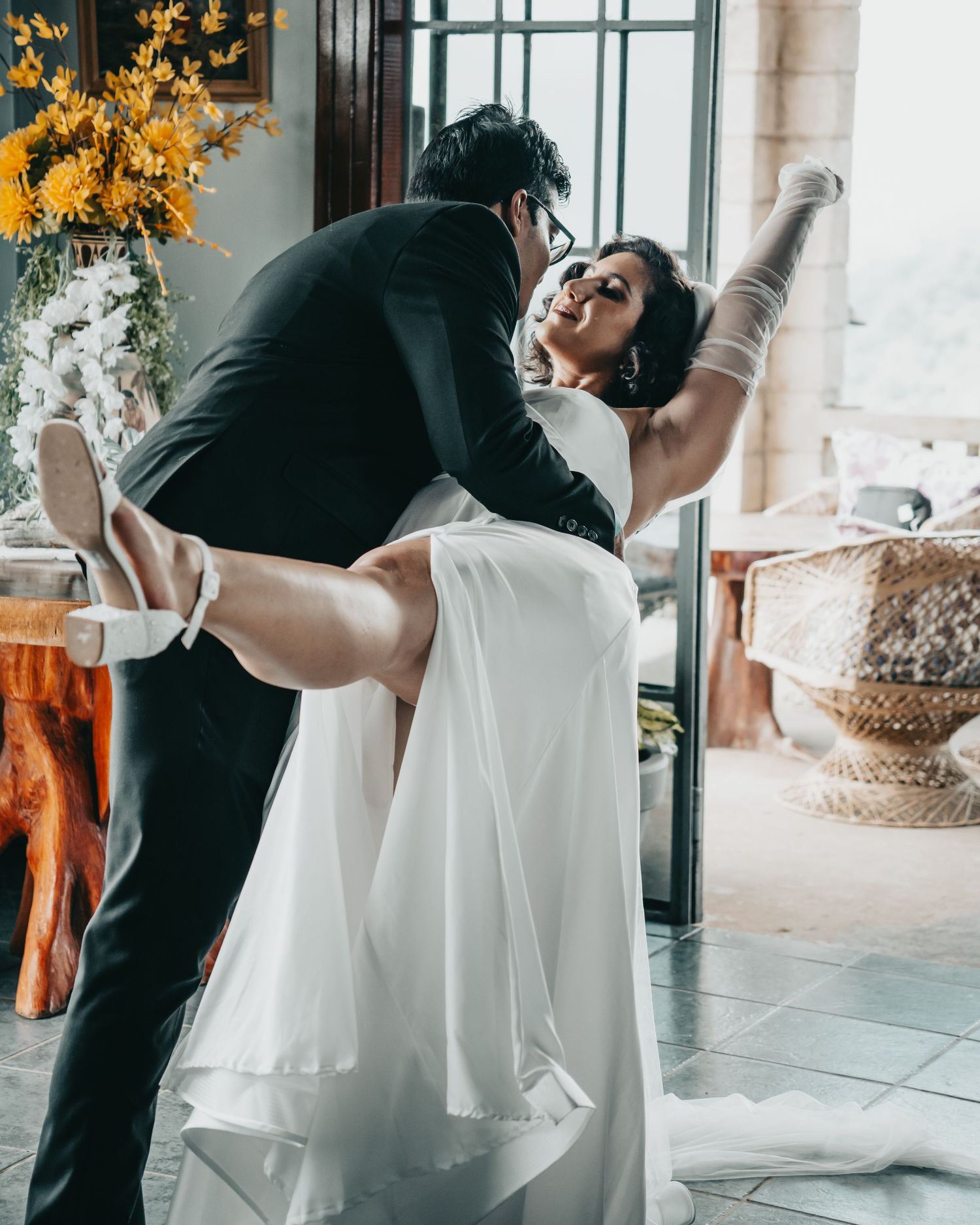 A dramatic wedding dance dip pose captured in an indoor setting with autumn decor.