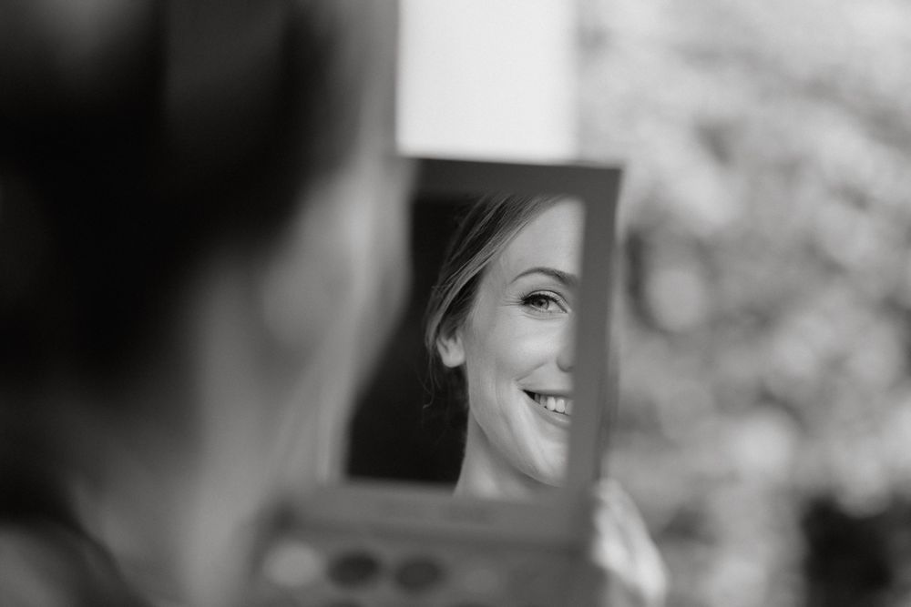 Artistic black and white shot of a reflection in a small mirror during wedding preparations.