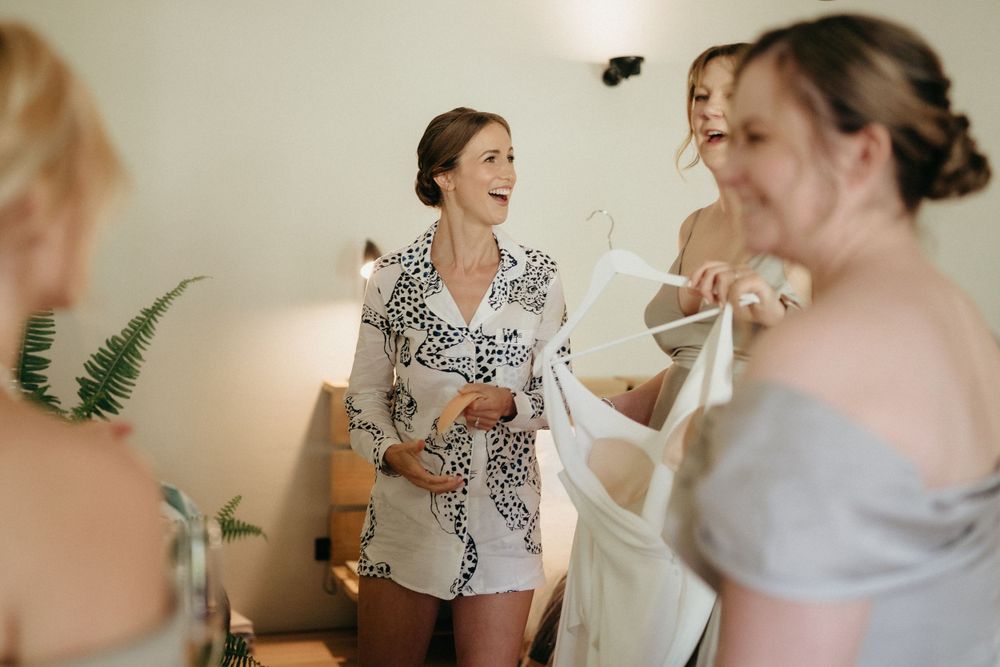 Wedding morning preparations show women laughing together in casual attire.
