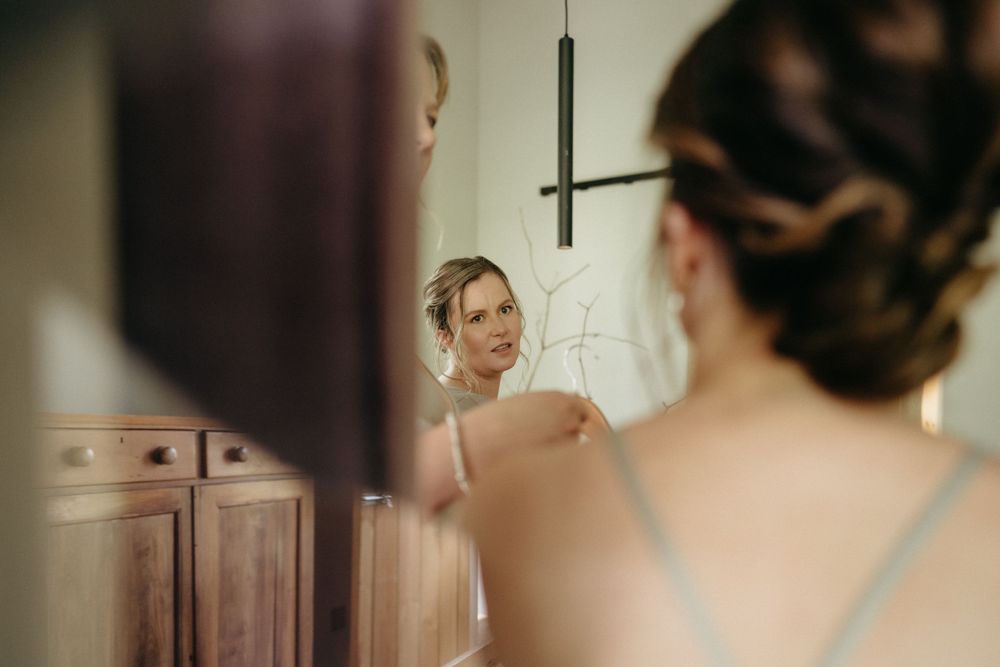 Soft focus reflection of wedding preparations in a vintage wooden vanity mirror.