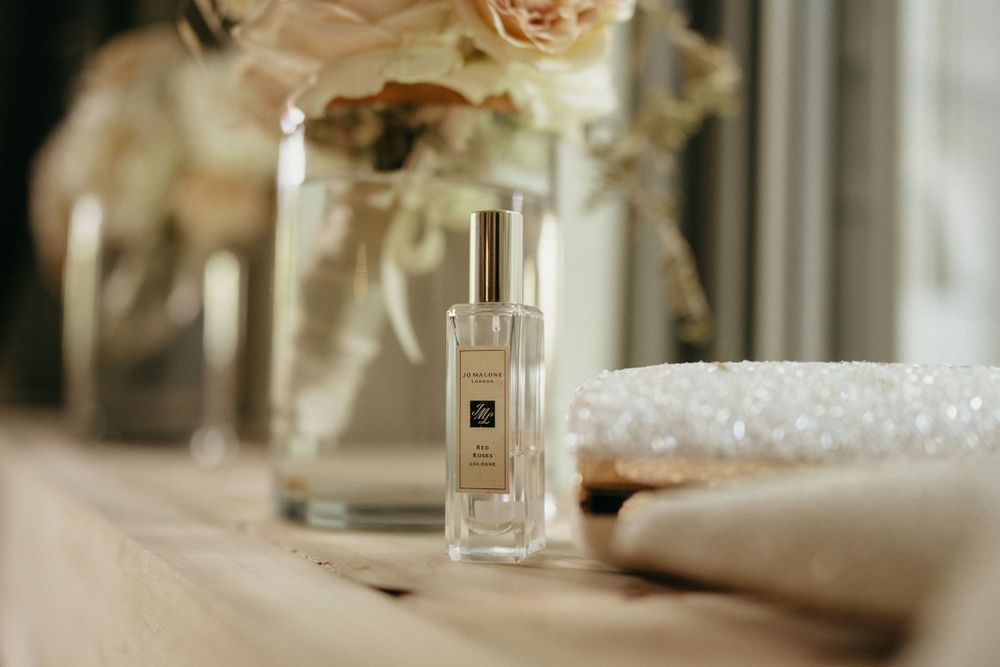 Elegant perfume bottle and roses arranged on a light-colored surface in soft lighting.