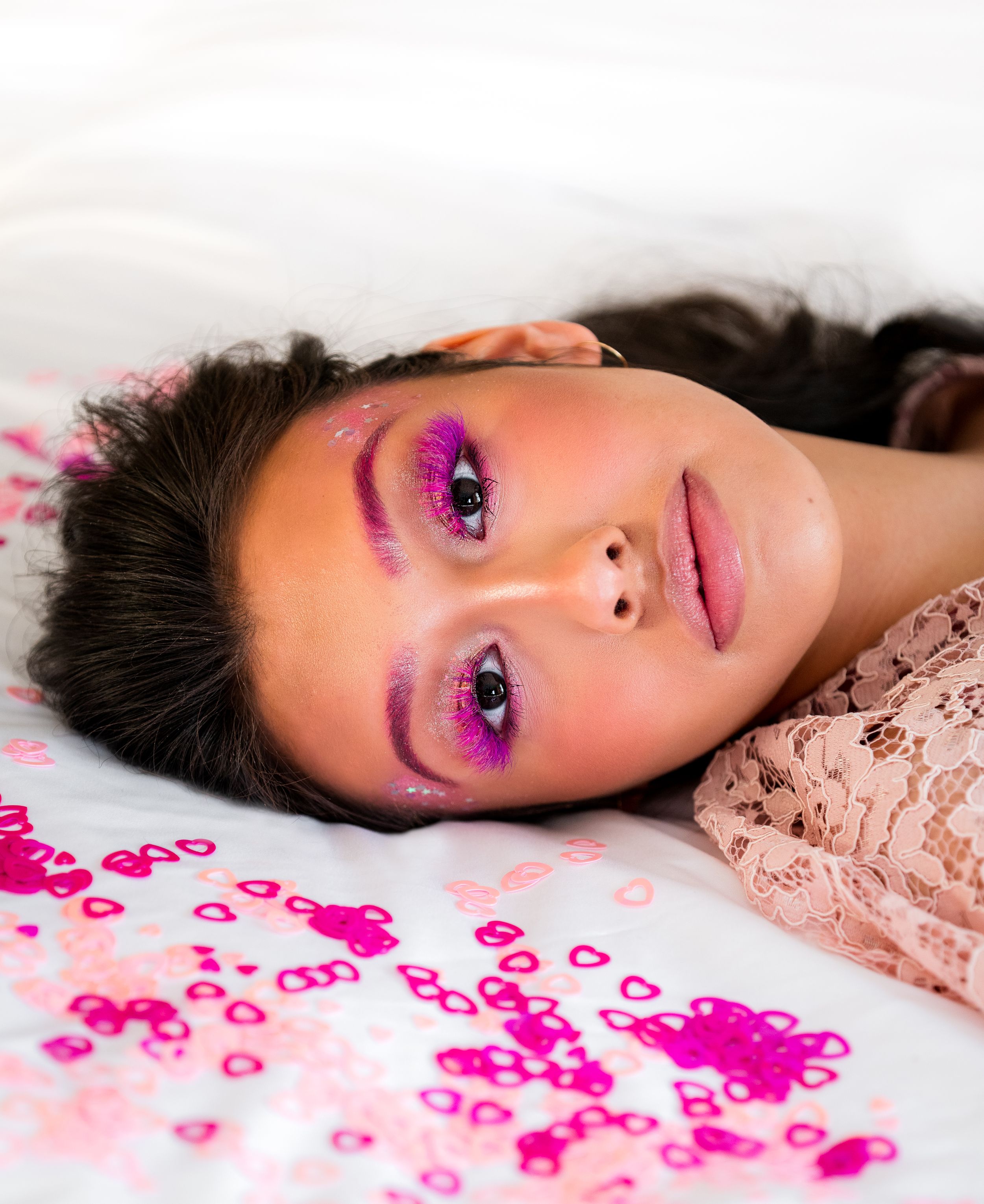 Close-up beauty shot featuring vibrant pink makeup and glitter details.