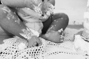 Mani del bambino che giocano con panna una superficie di pizzo bianco.
