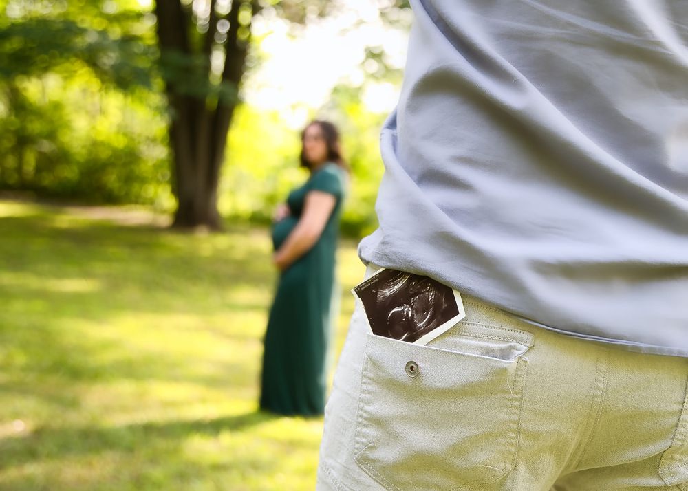 Close-up of a hidden engagement ring in a pocket with a blurred green background.