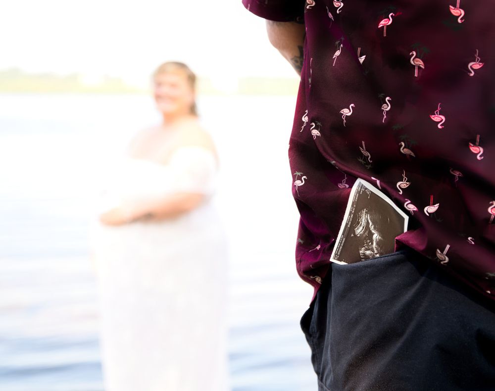 Ultrasound photo in pocket with soft focus white dress in background near water.
