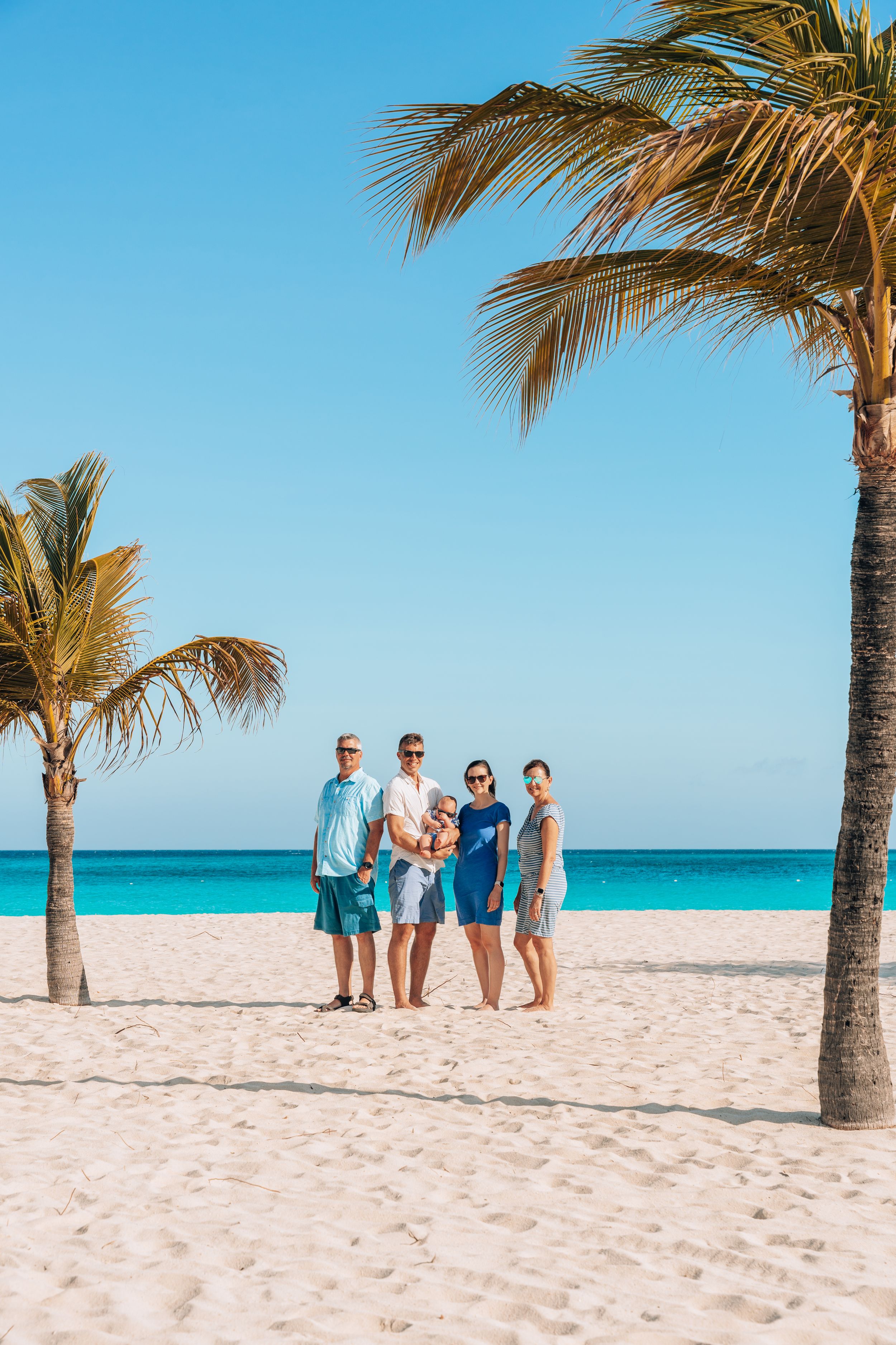 Group enjoying a tropical beach vacation with palm trees, white sand and turquoise waters in the background.