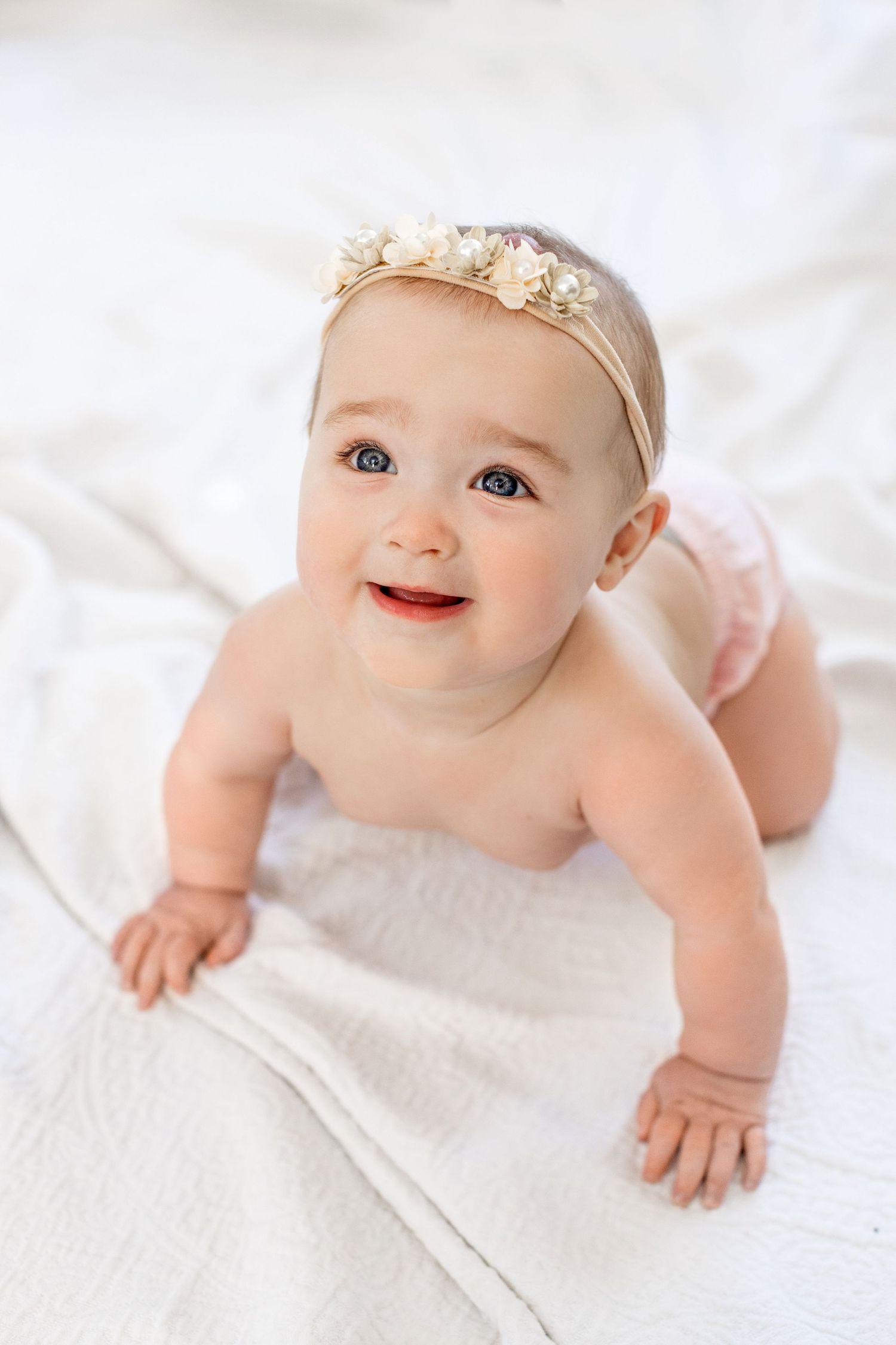 Lifestyle session of baby crawling on a white blanket in Springfield, Missouri.